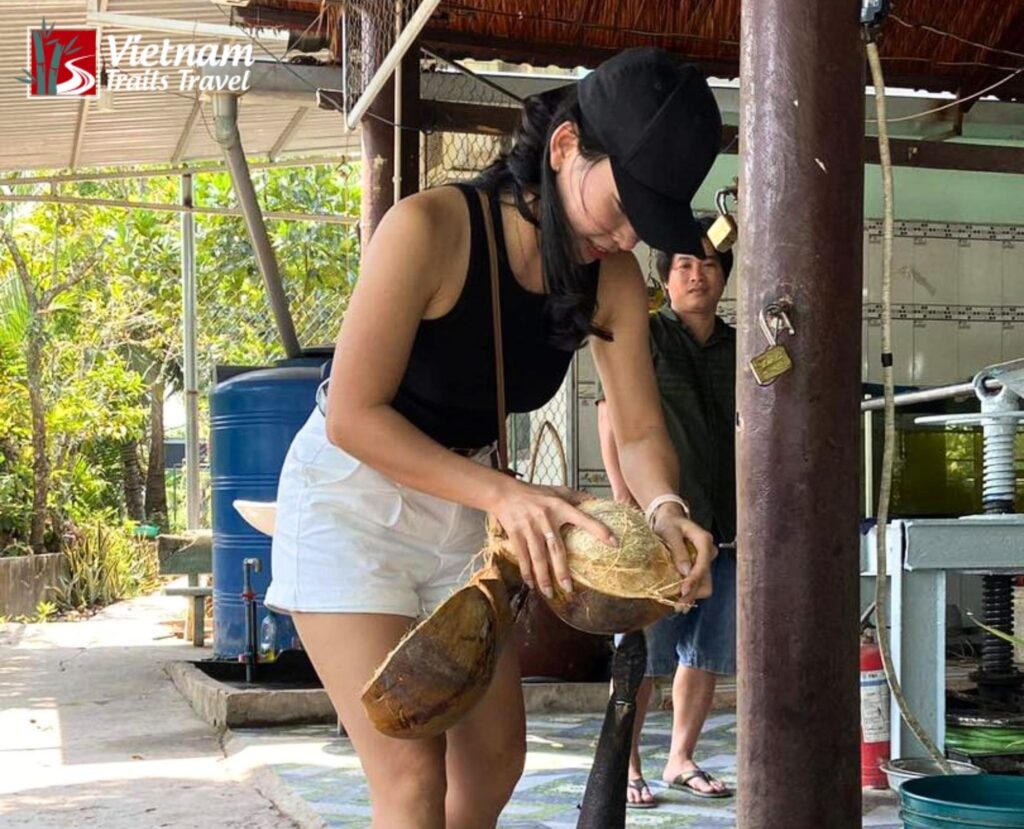 A foreign tourist learning how to peel a coconut at a traditional candy workshop