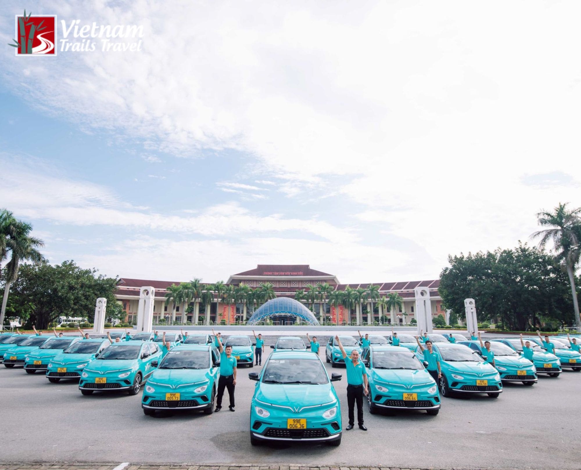 A line of Xanh SM electric taxis and drivers posing in front of a landmark building in Vietnam