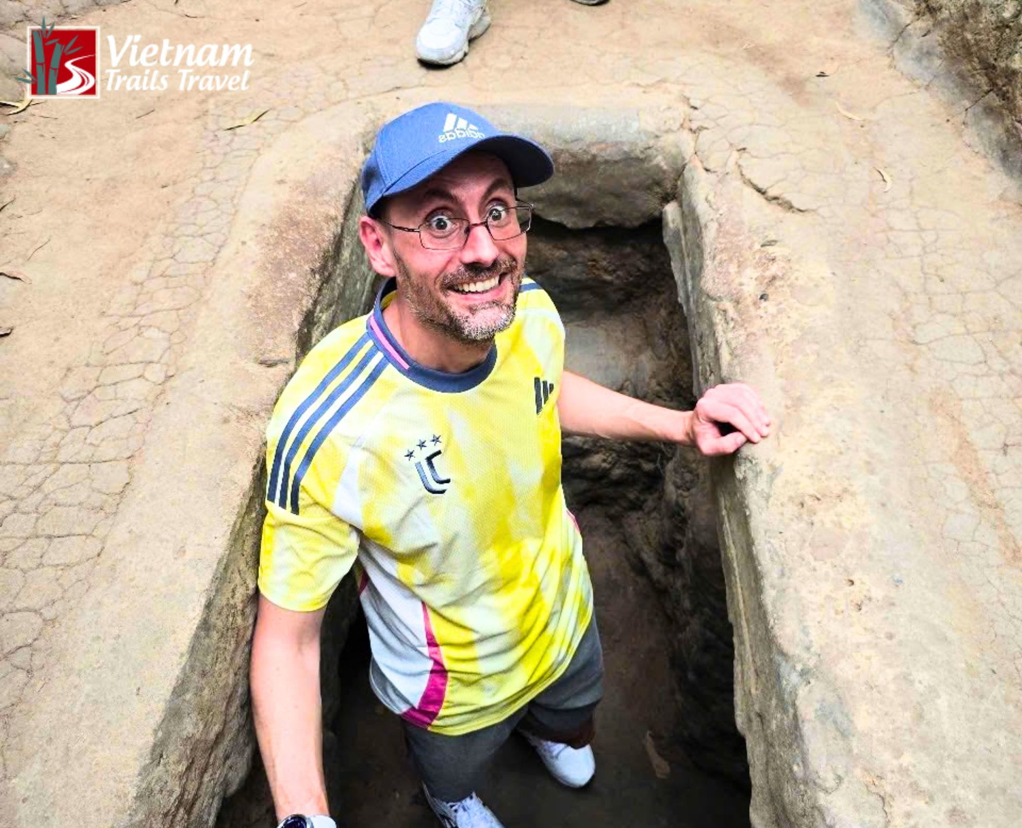 A smiling male tourist exploring the underground network at Cu Chi Tunnels