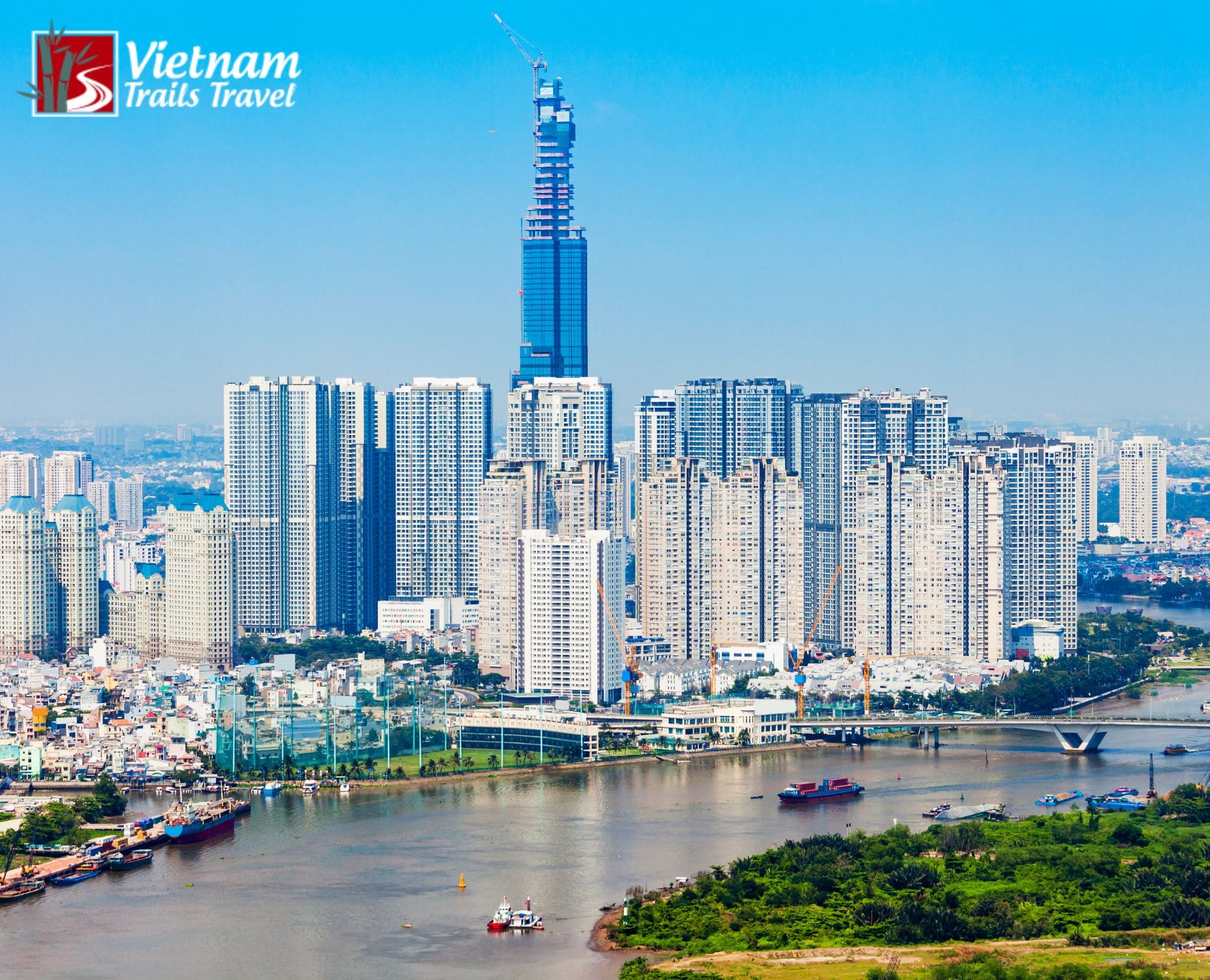 Aerial view of Ho Chi Minh City's urban development with residential skyscrapers, a bridge, and boats on the river