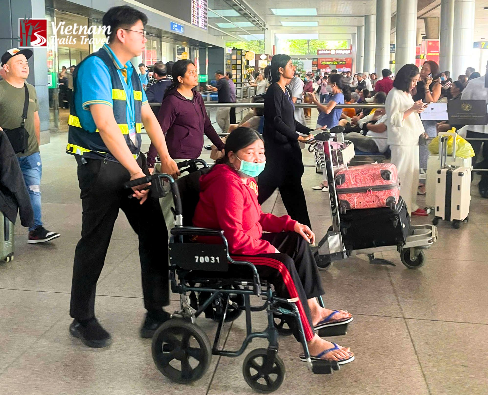 Tan Son Nhat Airport Fast Track Service assistant pushing a traveler in a wheelchair through a busy terminal