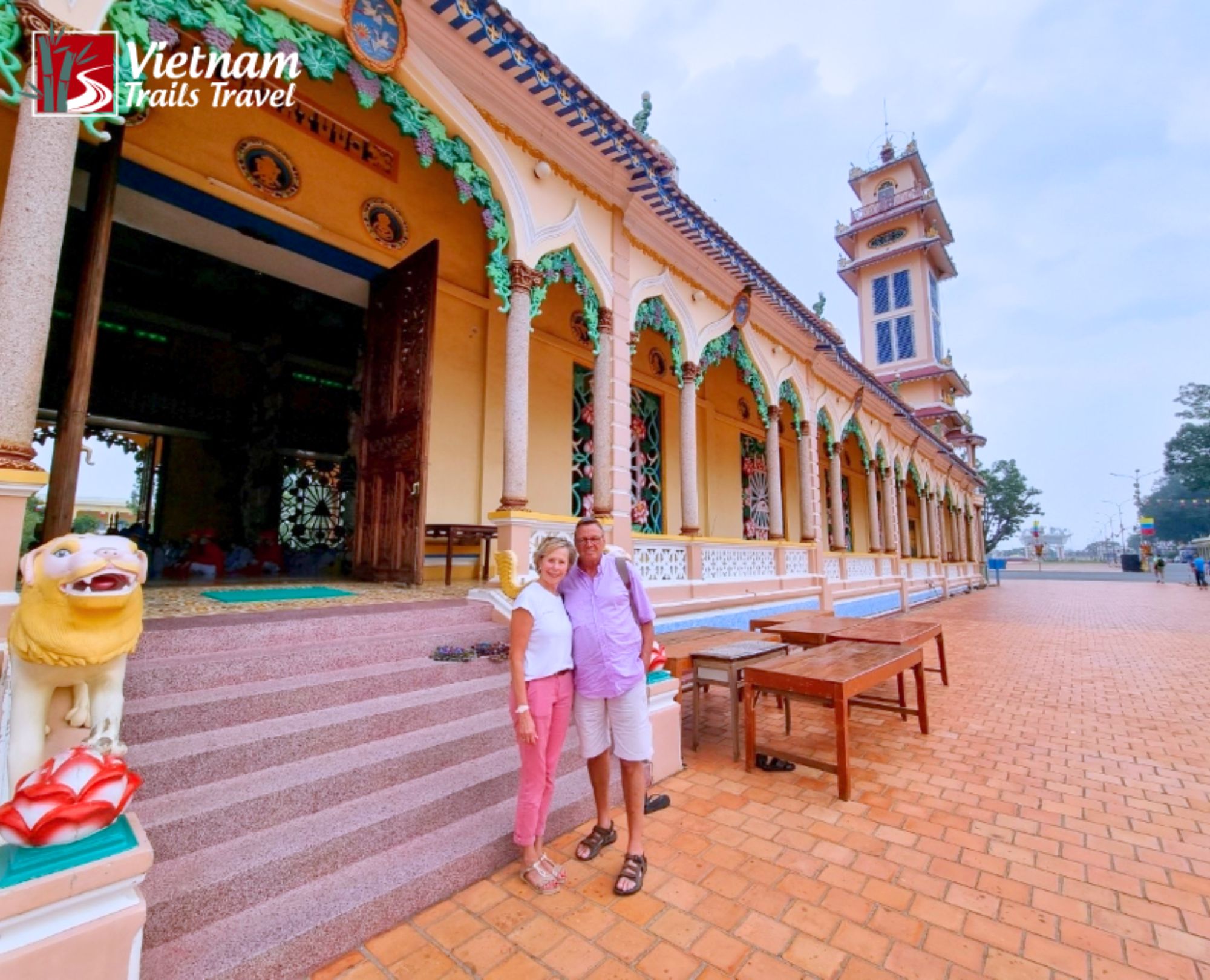 Tourists posing in front of the colorful Cao Dai Temple entrance