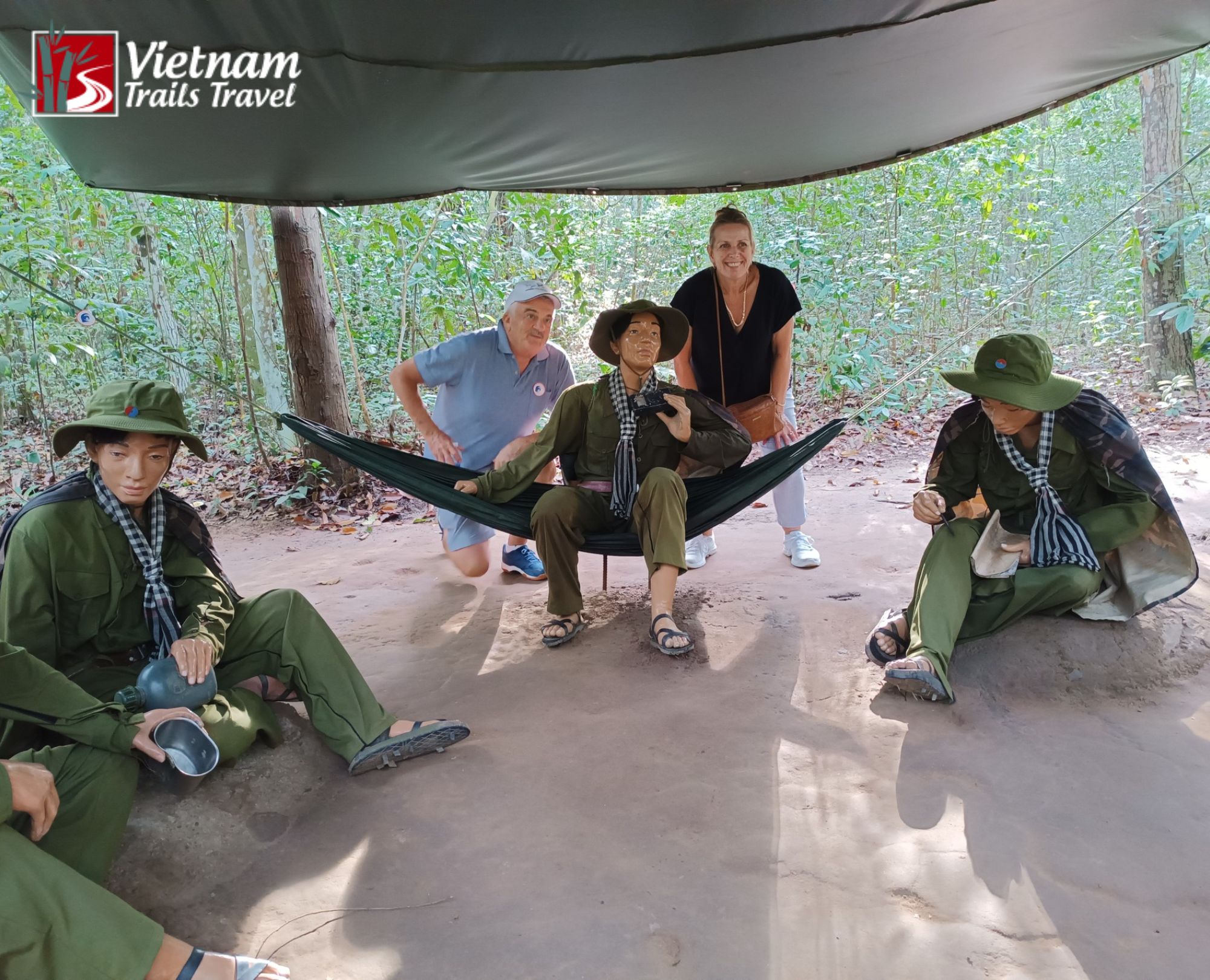 Tourists posing with life-sized mannequins of Vietnamese soldiers at a camp display in the Cu Chi Tunnels