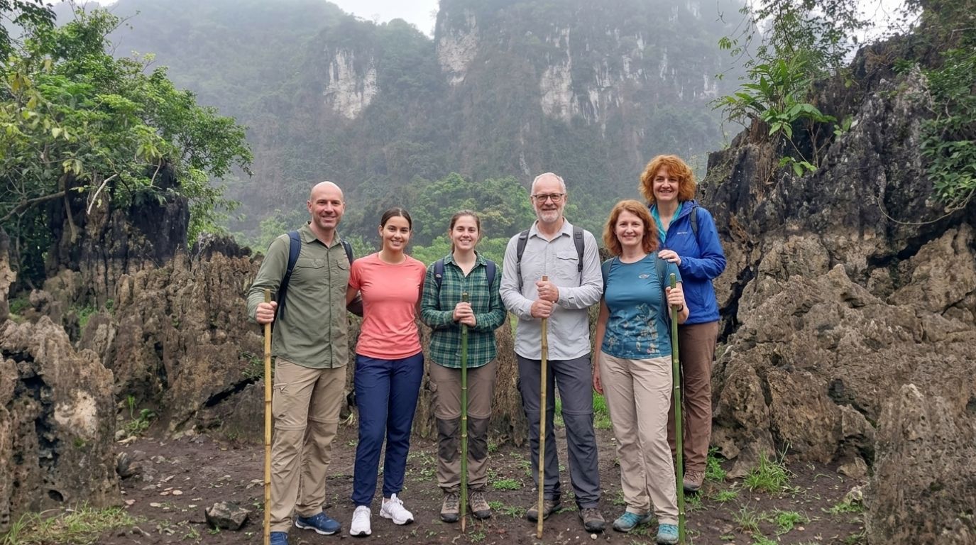 A group of tourists with walking sticks posing among jagged limestone rocks while trekking in Cat Ba National Park