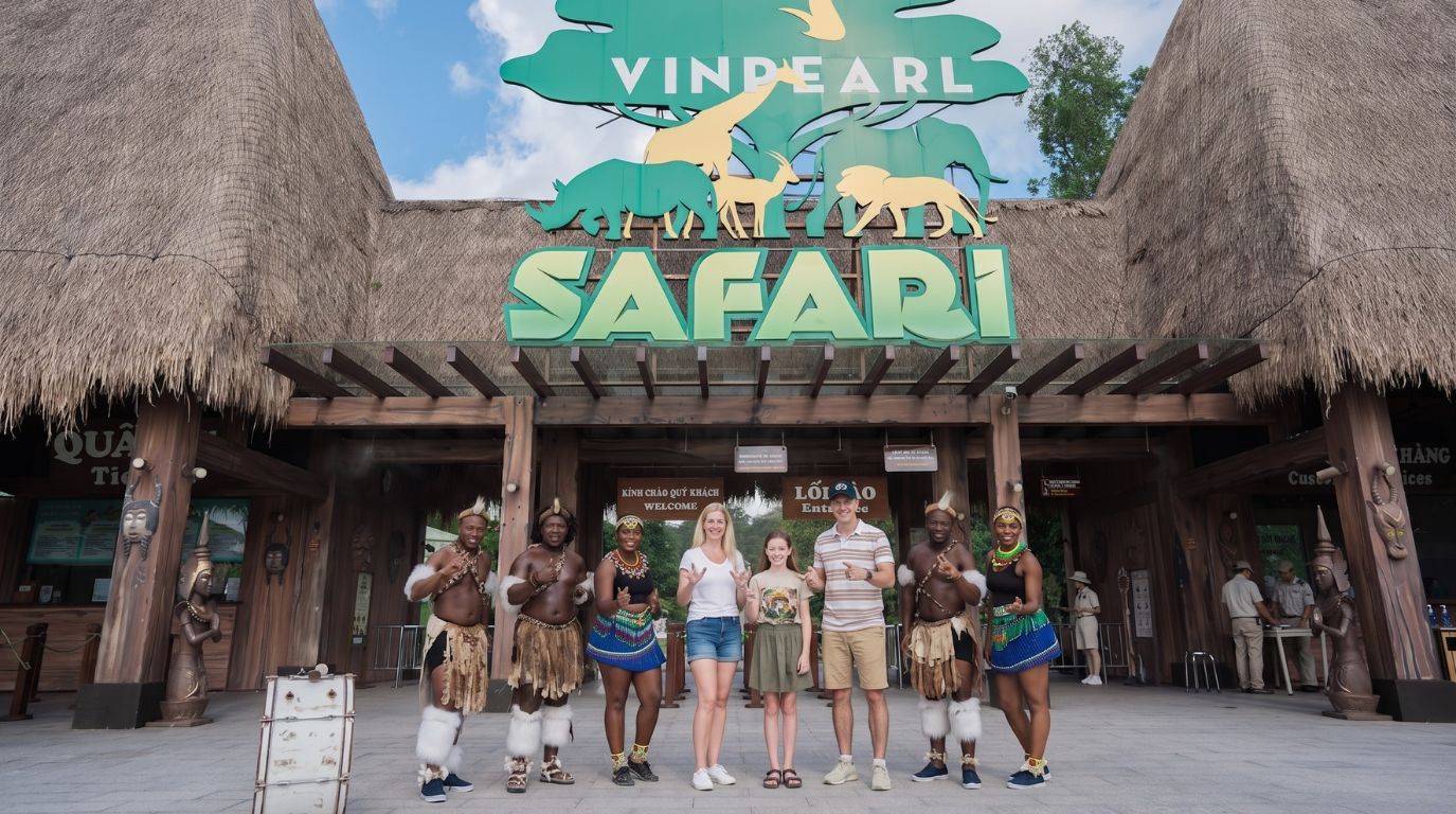 A tourist family posing with traditional tribal dancers at the main entrance gate of Vinpearl Safari in Phu Quoc.