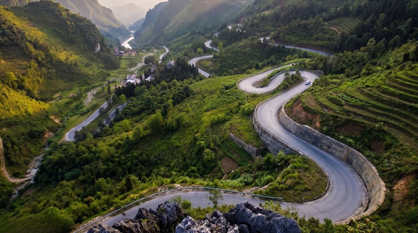 Aerial view of Ma Pi Leng Pass winding mountain pass road cutting through the lush green limestone mountains of Ha Giang