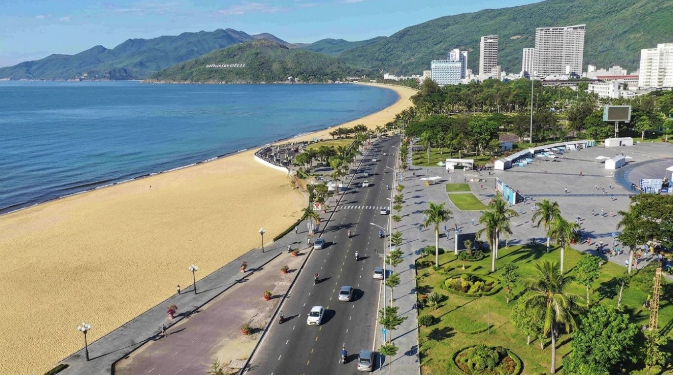 Aerial view of Xuan Dieu coastal road running alongside a sandy beach and city skyline in Quy Nhon