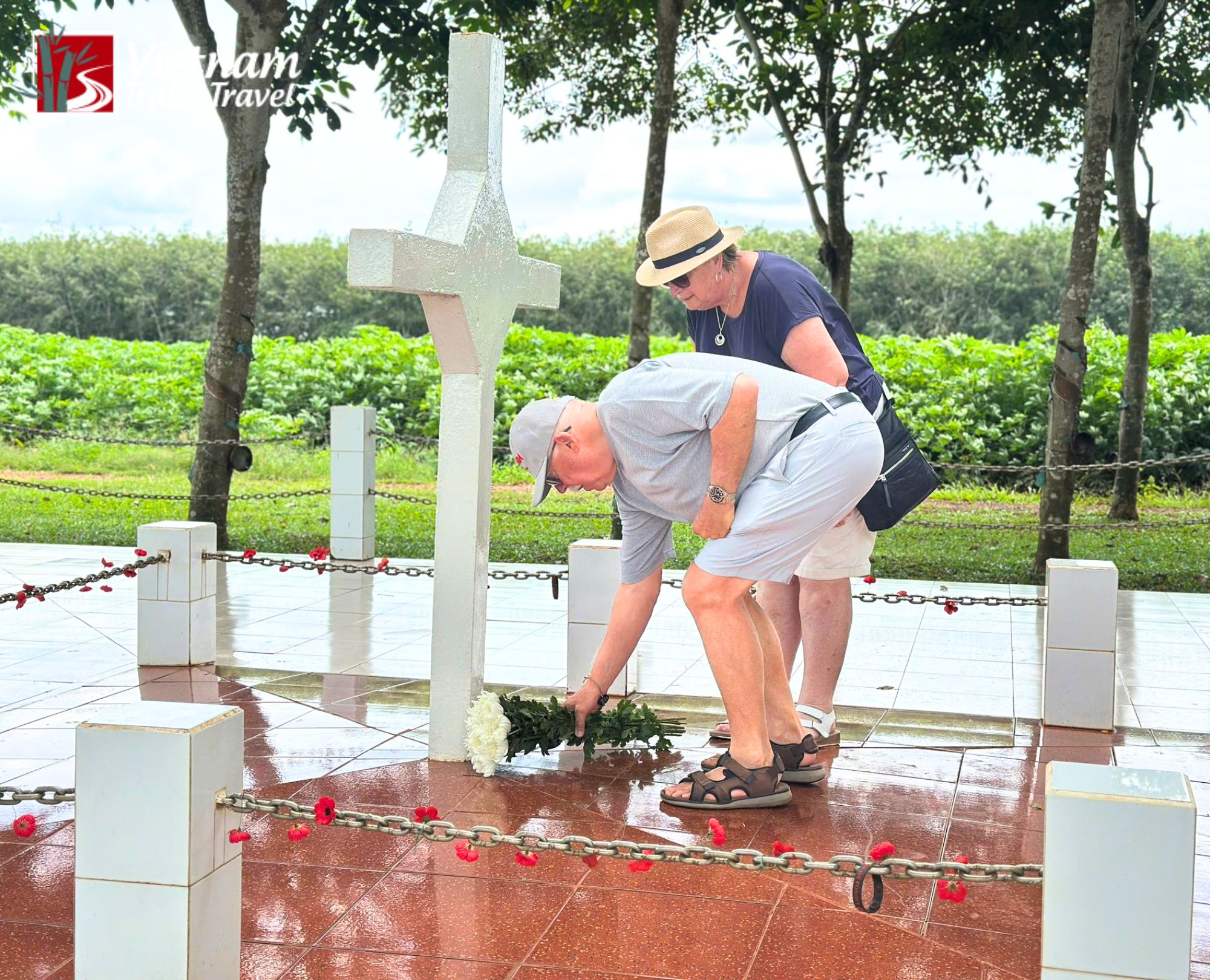 Australian travelers paying their respects and laying flowers at the Long Tan Battle memorial cross, a significant historical site for veterans in Vietnam