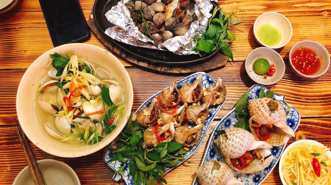 Authentic local seafood experience in Mui Ne featuring fresh clams, snails, and dipping sauces