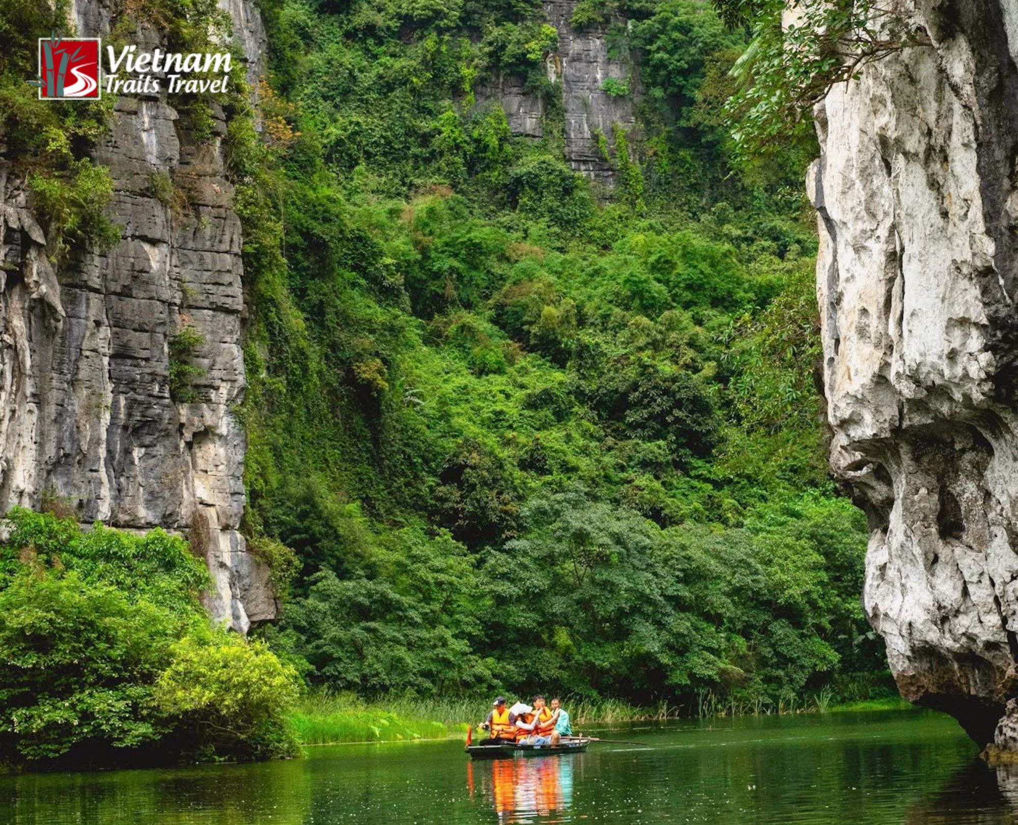 Boat tour on emerald green water between dramatic limestone karsts in Trang An