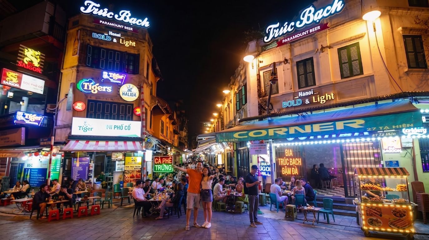 Bustling night view of Ta Hien street in Hanoi filled with glowing neon beer signs, a glowing street food cart, and locals and tourists experiencing the city's nightlife.