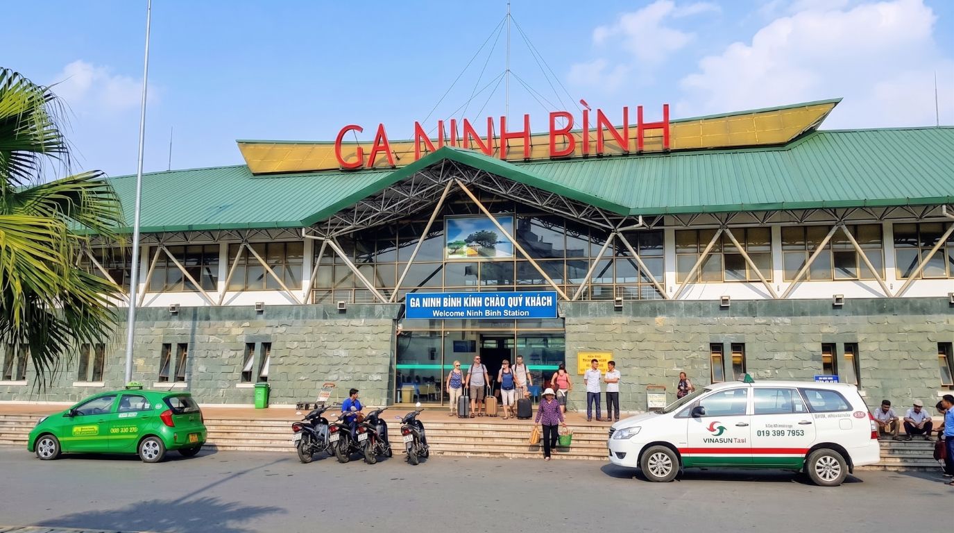 Exterior view of Ninh Binh Railway Station with arriving tourists and waiting taxis at the main entrance
