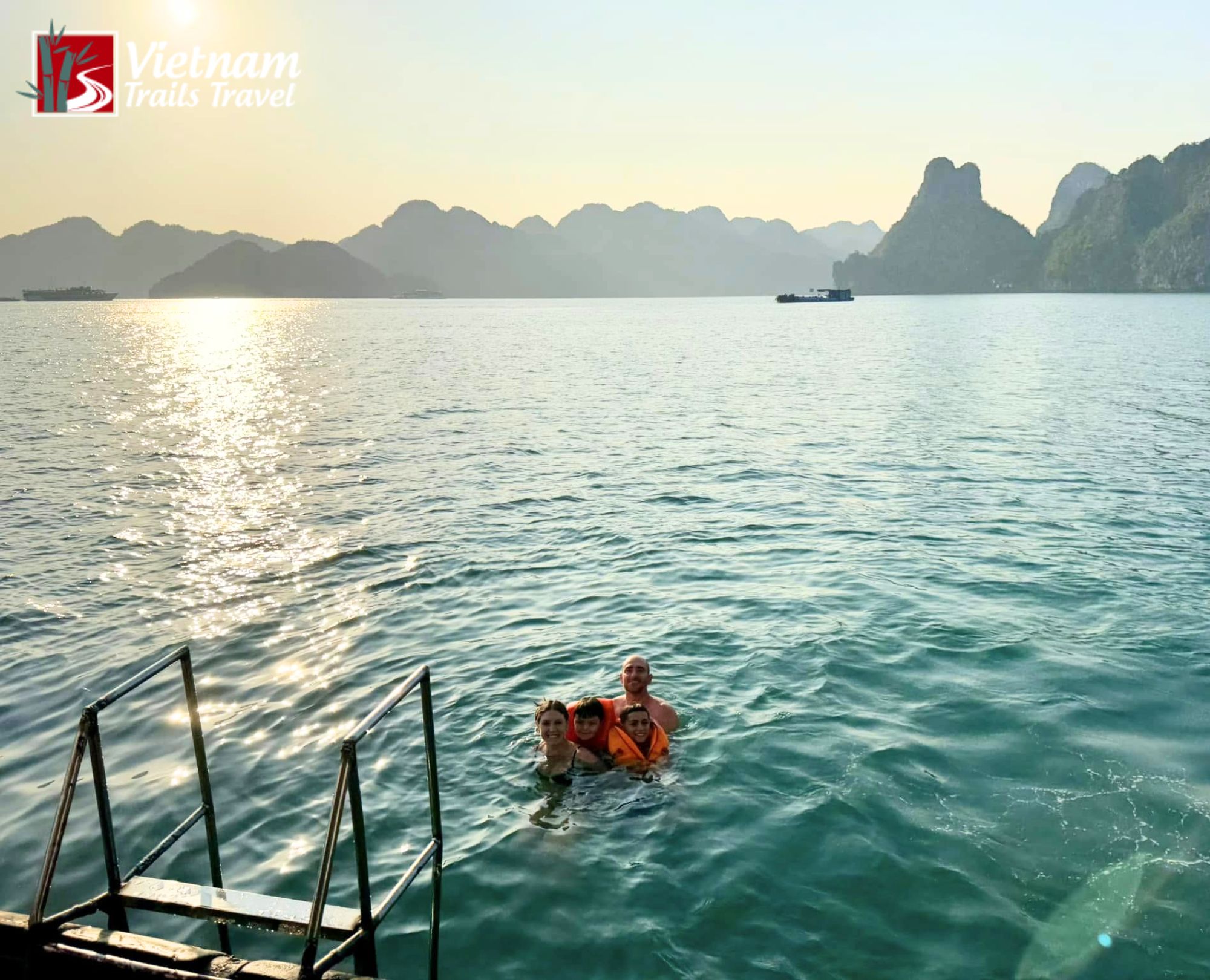 Family swimming in Ha Long Bay at sunrise with limestone karst islands