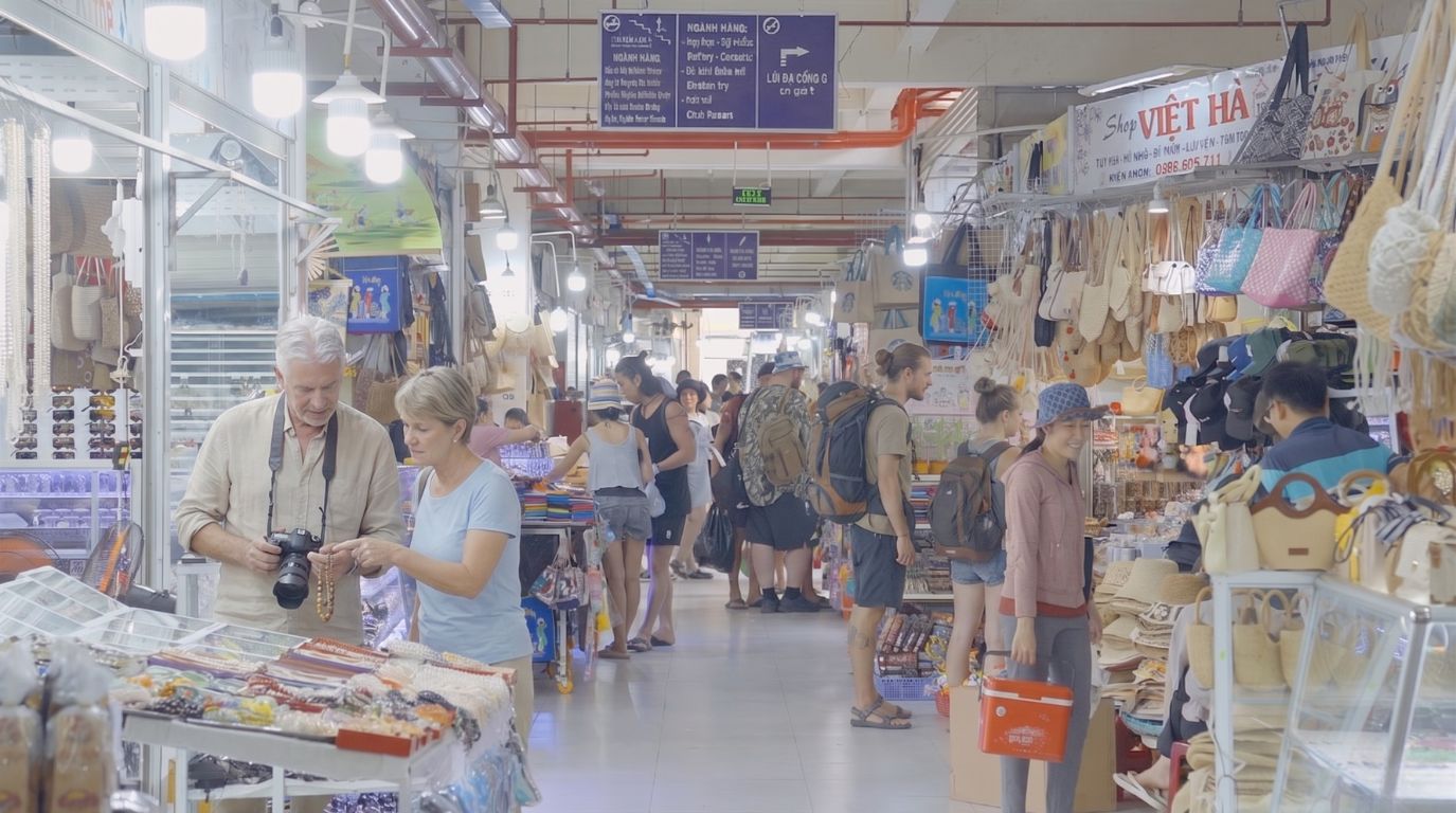 Foreign tourists shopping for souvenirs, local crafts, and woven bags at the bustling Dam Market in Nha Trang
