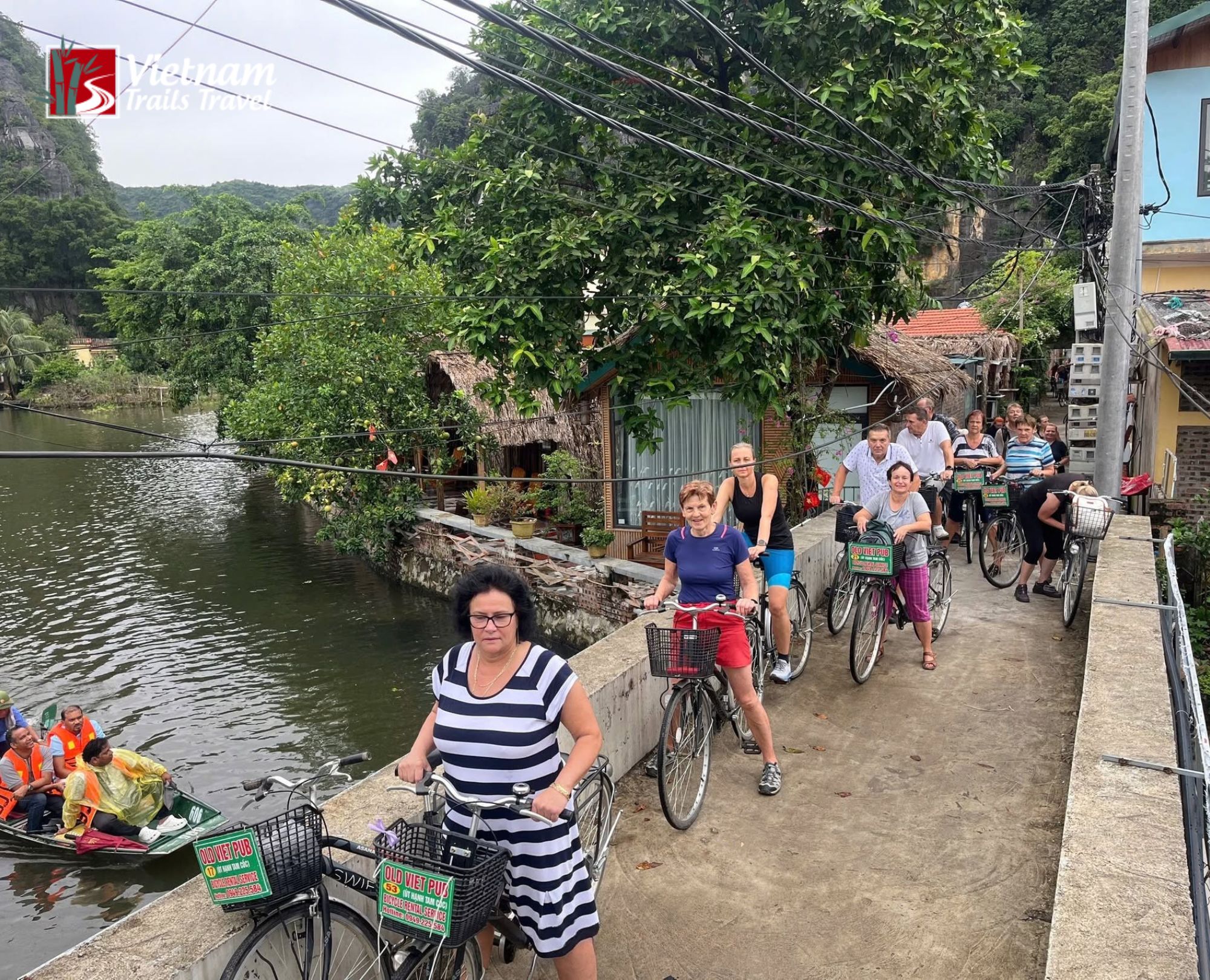 Group cycling tour on concrete path along canal in Ninh Binh