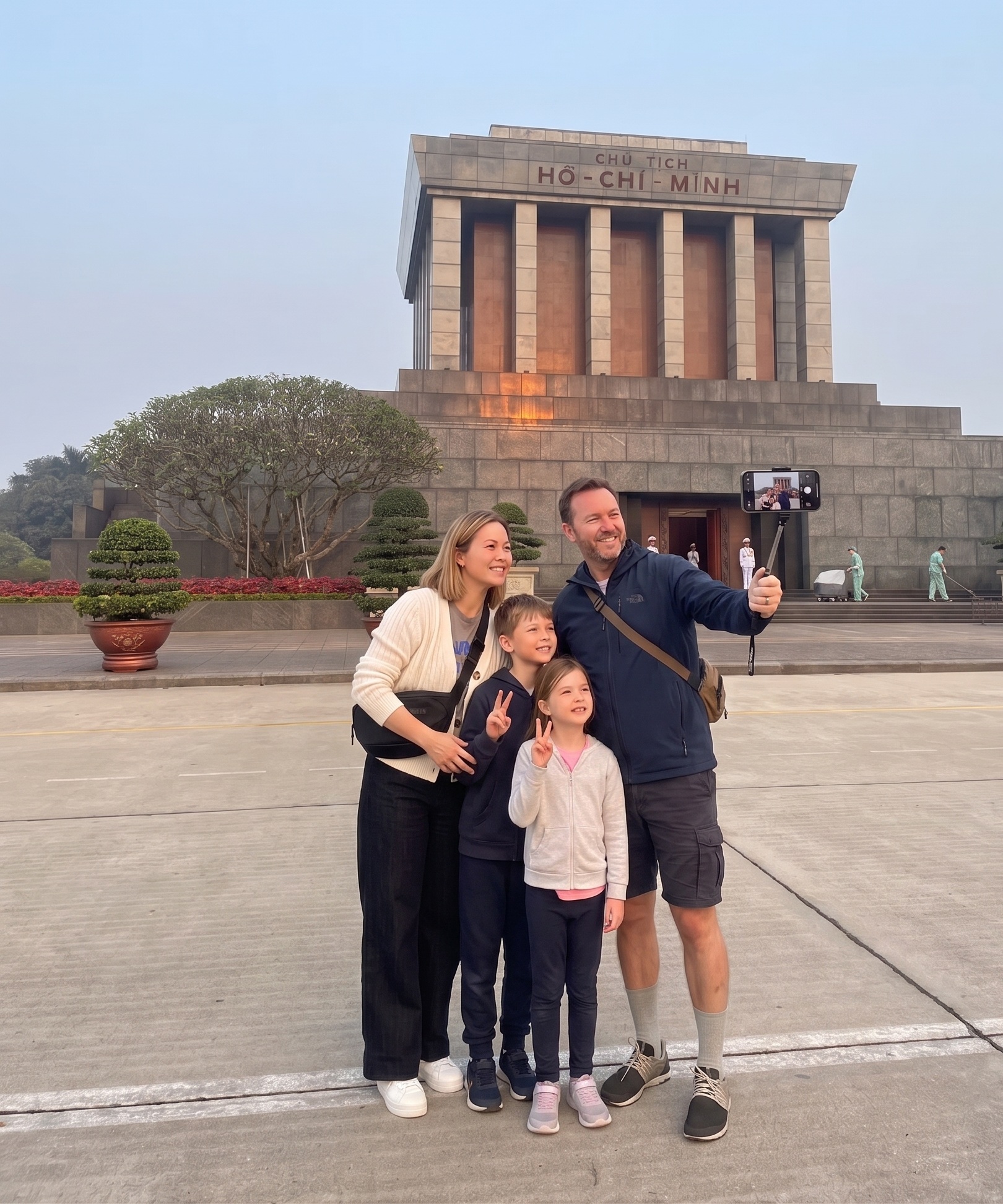 Happy foreign family taking a selfie together in front of the historic Ho Chi Minh Mausoleum at Ba Dinh Square in Hanoi