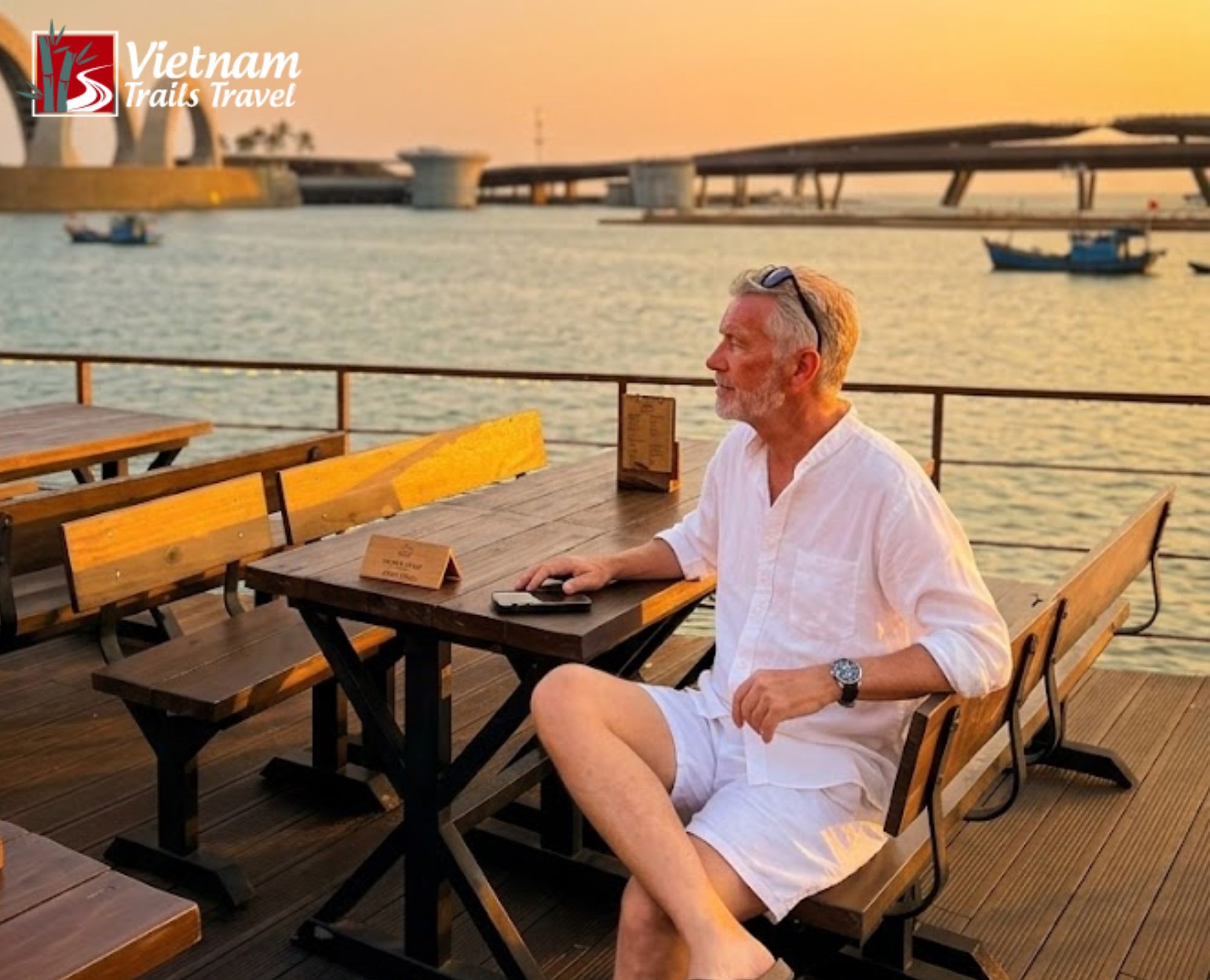 International traveler relaxing at a seaside cafe in Sunset Town with a panoramic view of the iconic Kiss Bridge