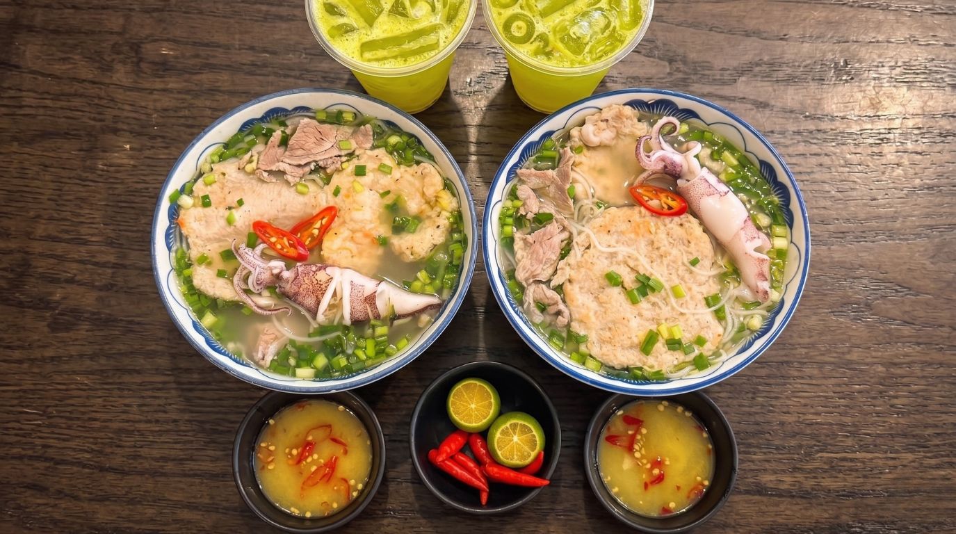 Top-down view of Bun Quay, Phu Quoc's signature seafood noodle soup featuring fresh squid, fish paste, and dipping sauce
