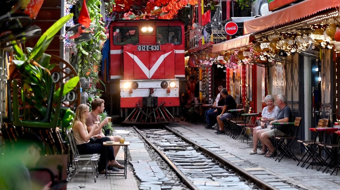 Tourists watching a red train pass through the famous narrow Train Street cafes in the Hanoi Old Quarter