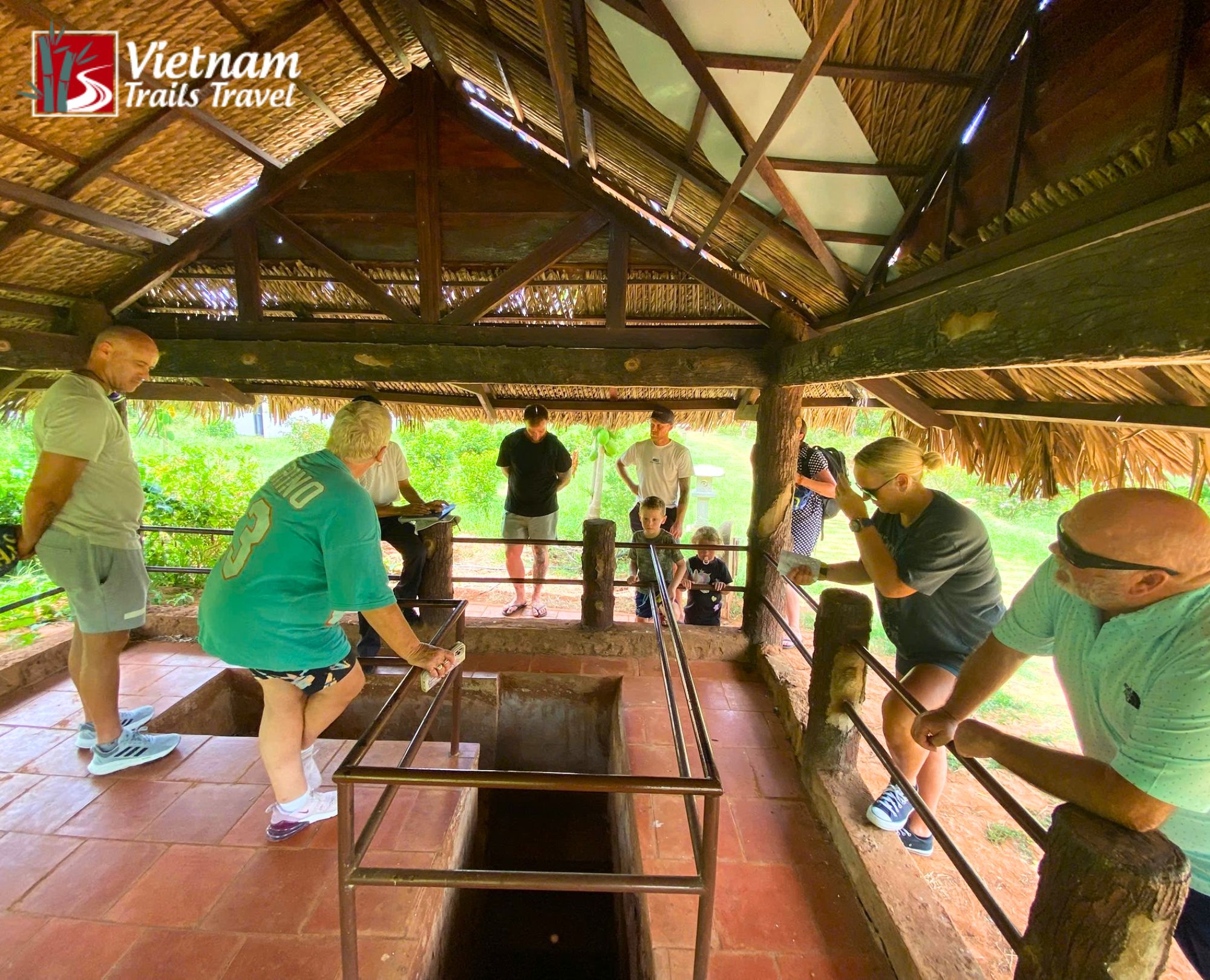Travelers gathering around a historic tunnel entrance at Long Phước, learning about the underground defense network during a guided tour