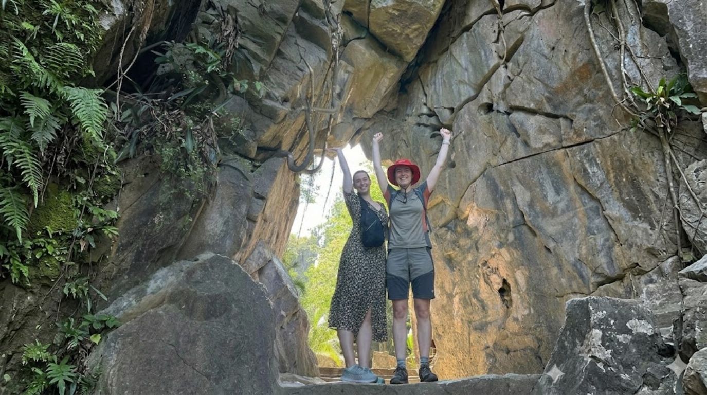 Two female tourists posing at a limestone cave entrance in Marble Mountains Da Nang