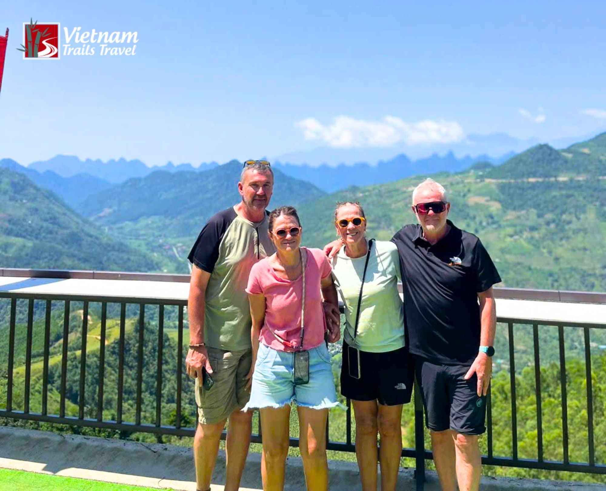 Group of tourists on a scenic overlook in Hà Giang, surrounded by vast mountain ranges and valleys