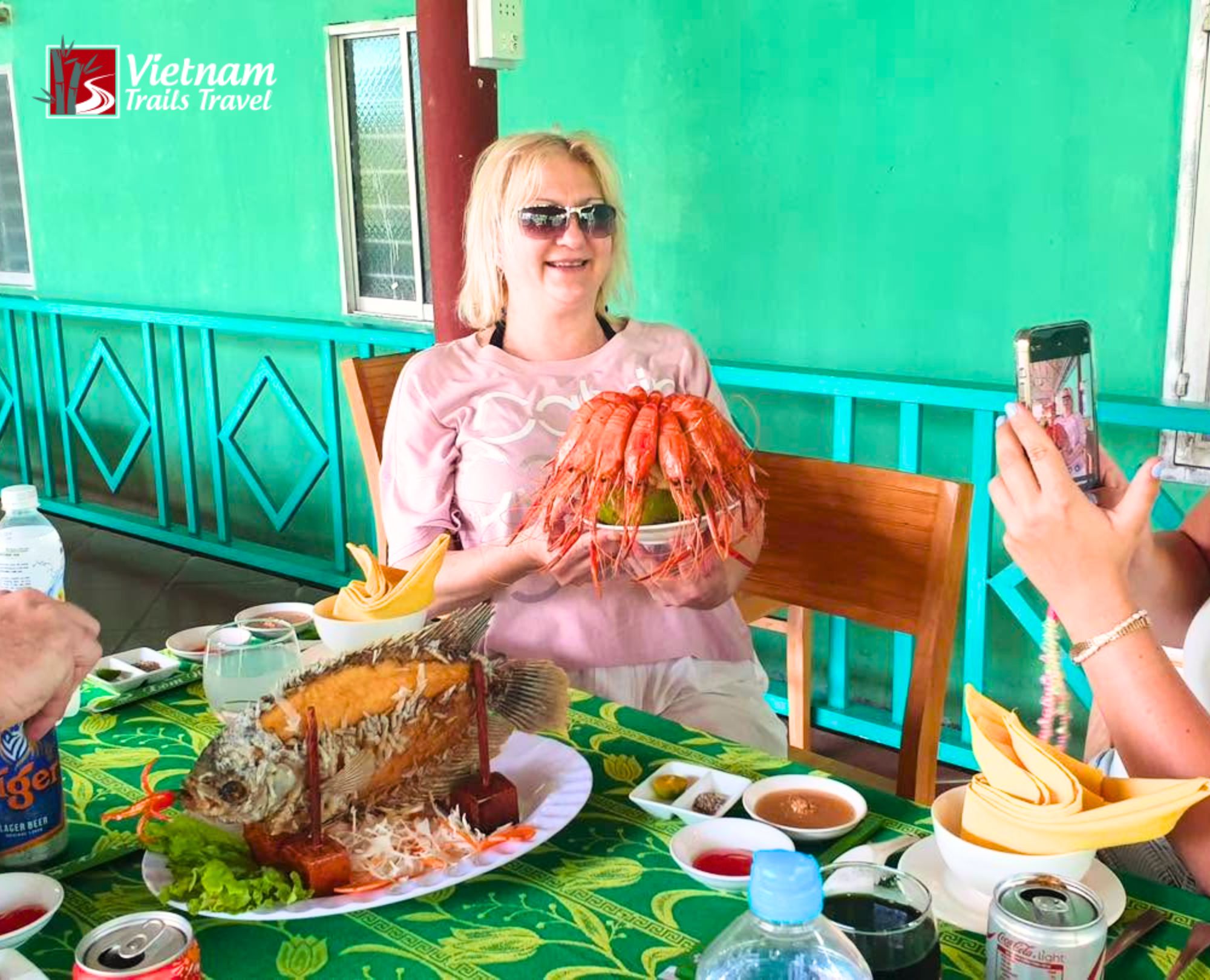 Happy traveler posing with a large shrimp dish and a fried ear elephant fish