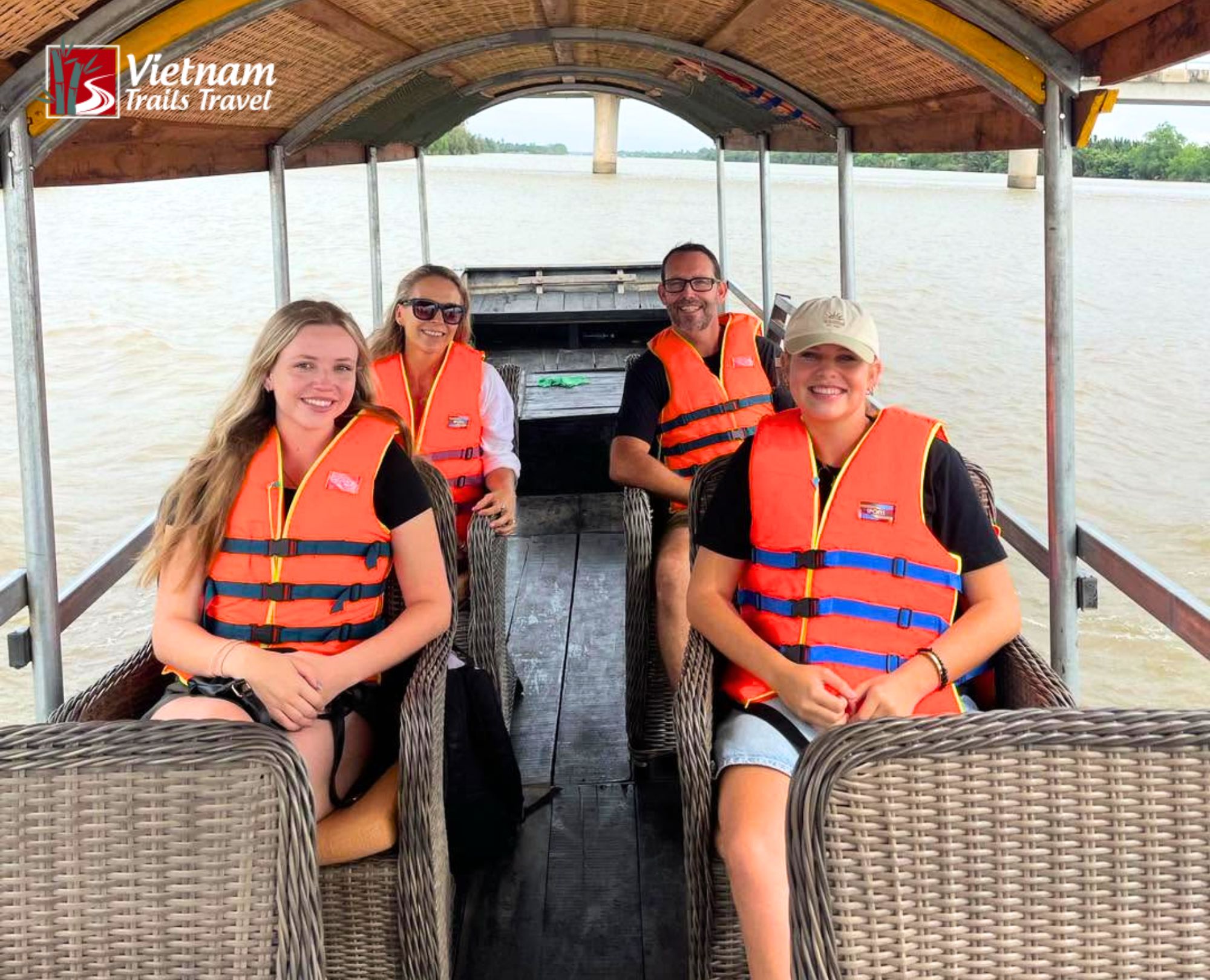 Happy travelers cruising the Mekong Delta's Tien River in a traditional boat