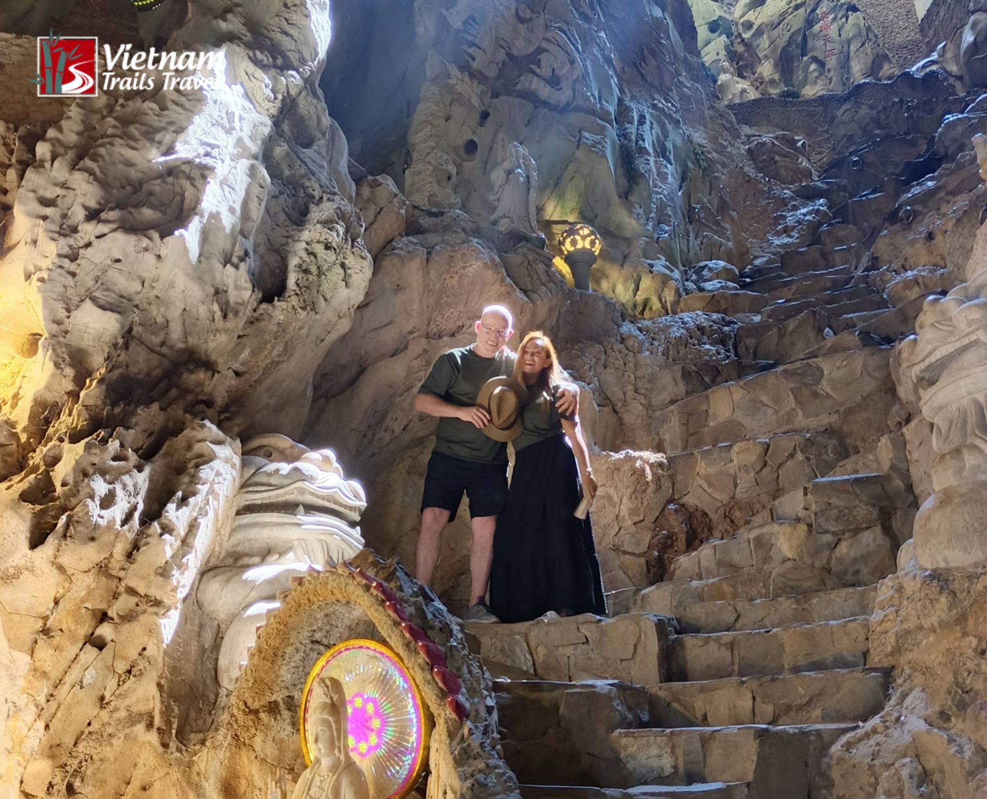 Tourists exploring the illuminated caves and Buddhist statues inside Marble Mountain