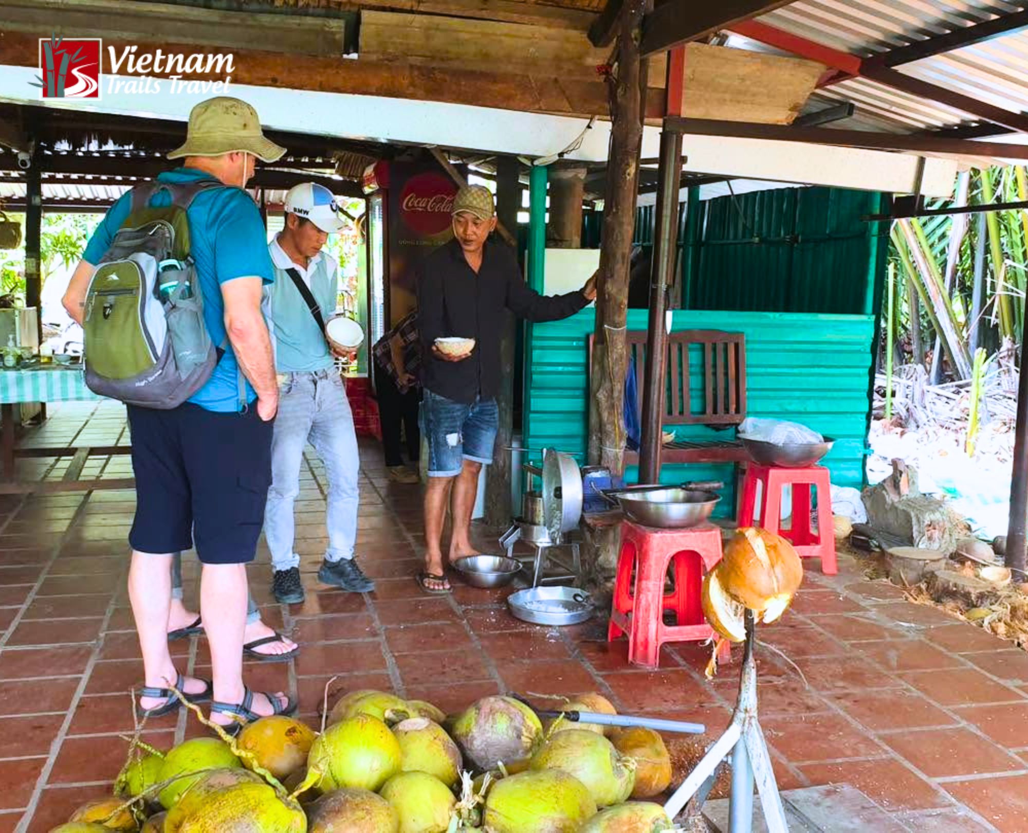 Travelers learning about coconut products from a local artisan at a rustic workshop