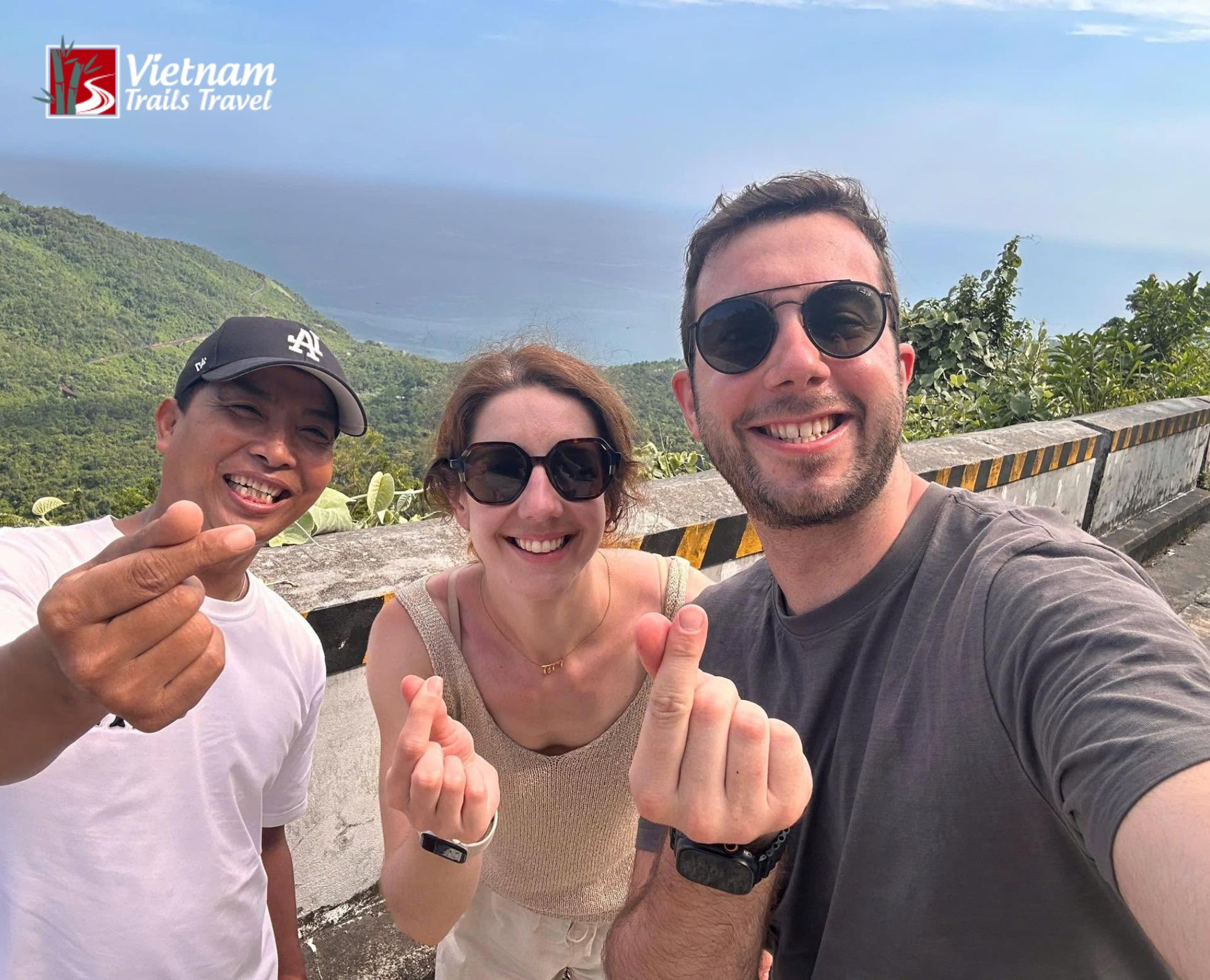 Travelers and their guide smiling at the Hai Van Pass viewpoint on the way to Da Nang