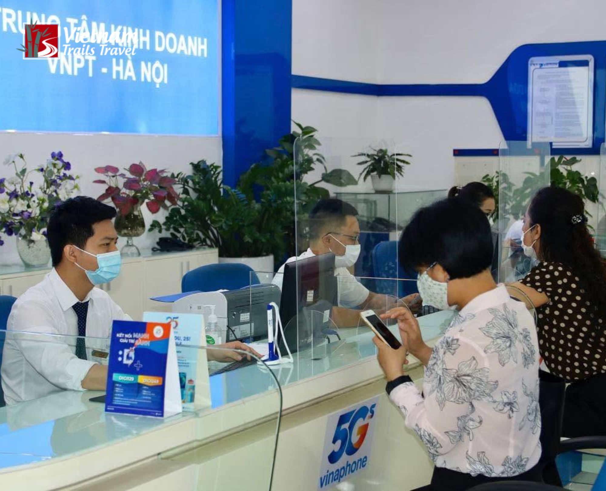 A Vinaphone employee is assisting a Japanese customer who has just arrived at the airport and is purchasing a tourist SIM card