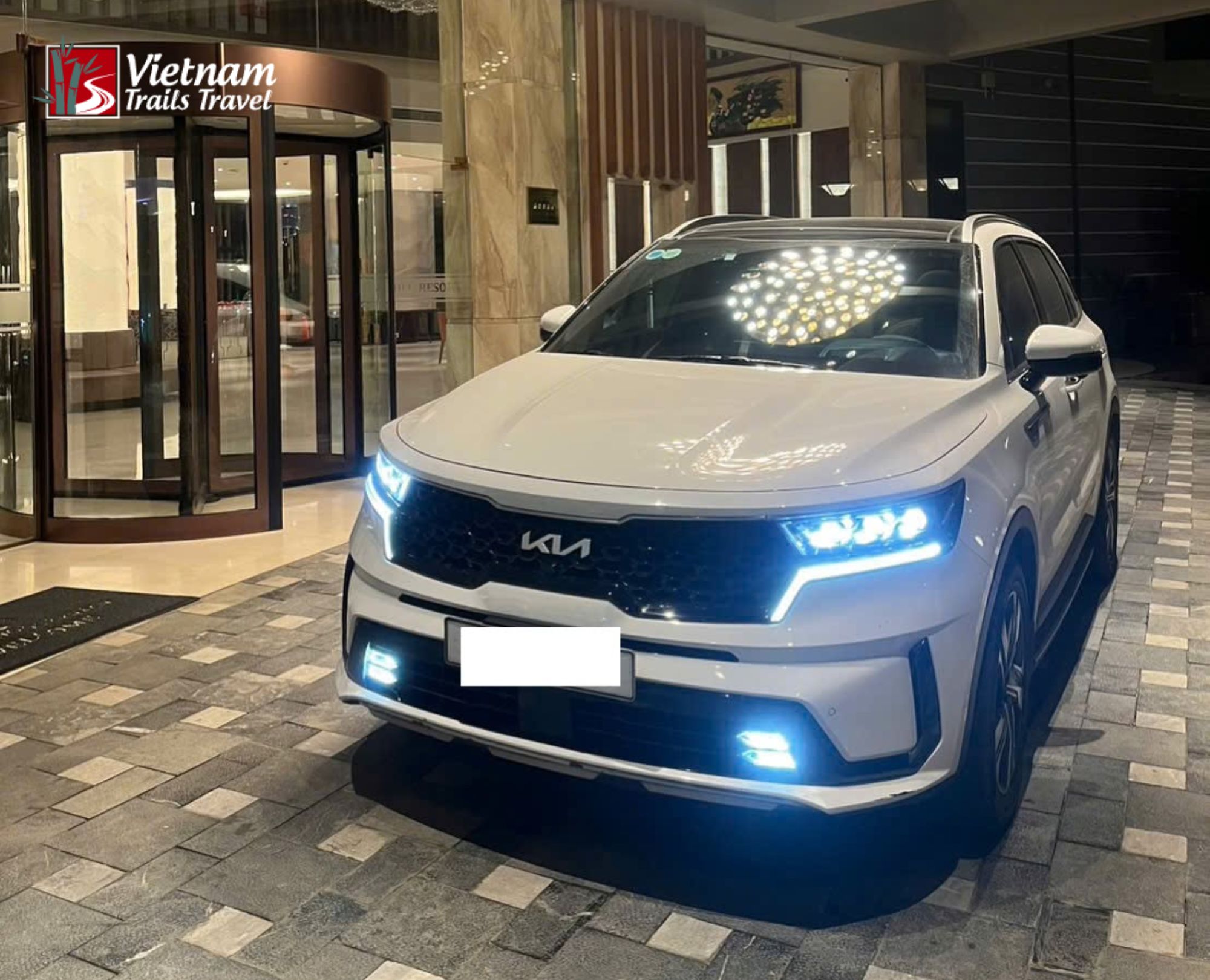 Private transfer vehicle outside a bright hotel entrance in Hanoi, preparing to shuttle travellers for their Sapa Trekking Tour departure