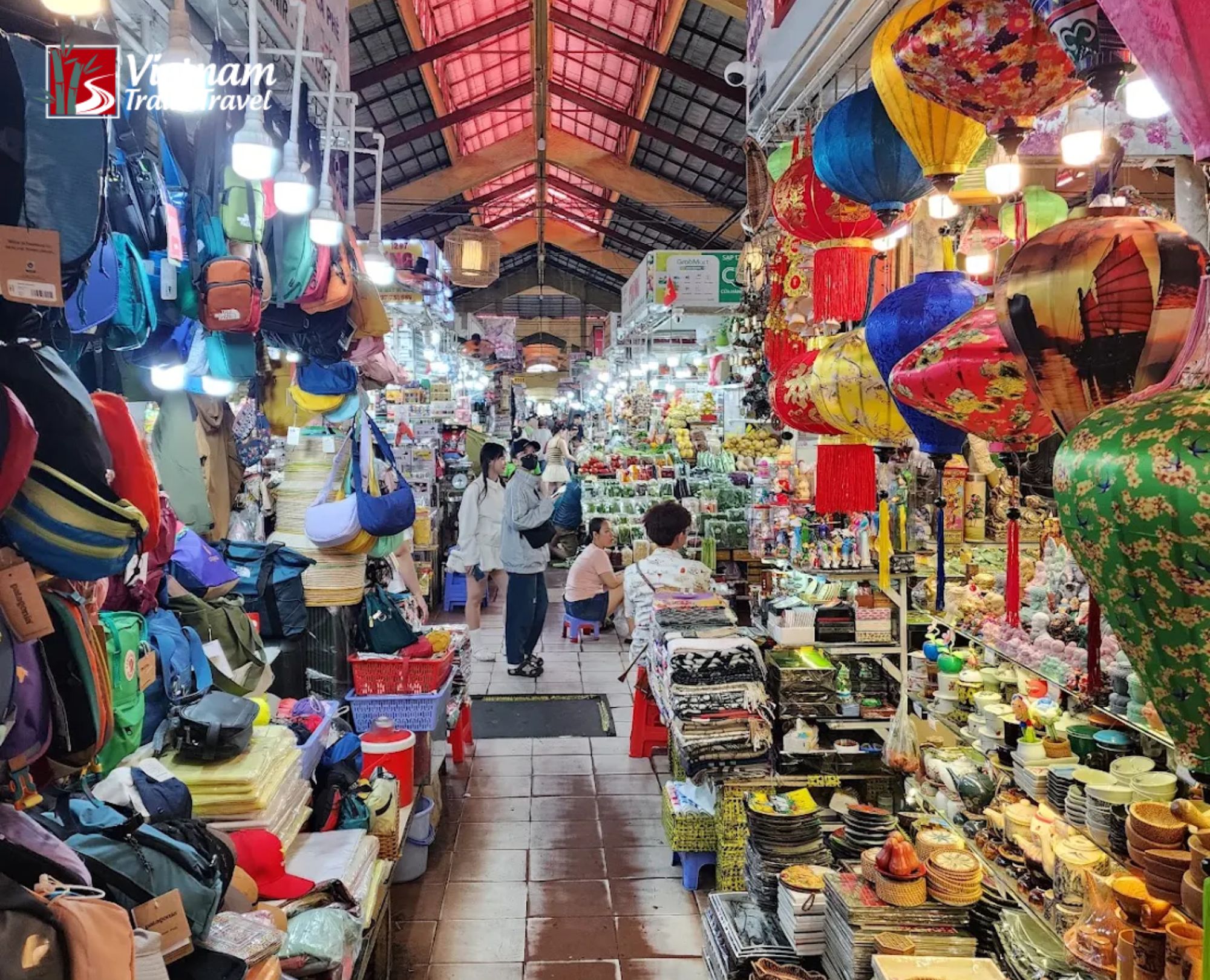 Busy indoor stalls with colorful lanterns and merchandise at Ben Thanh Market