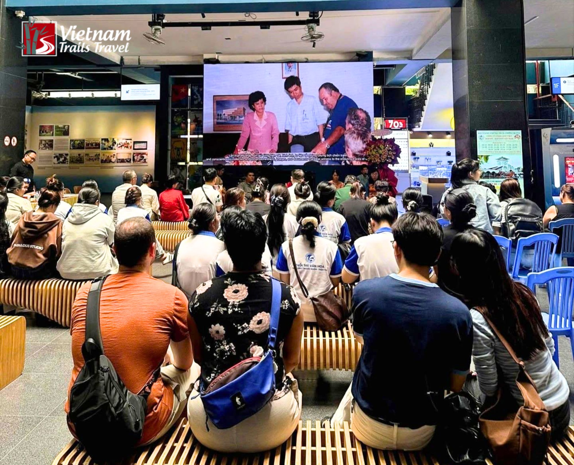 Visitors sitting and watching a presentation on the ground floor, illustrating typical museum crowd density during the day