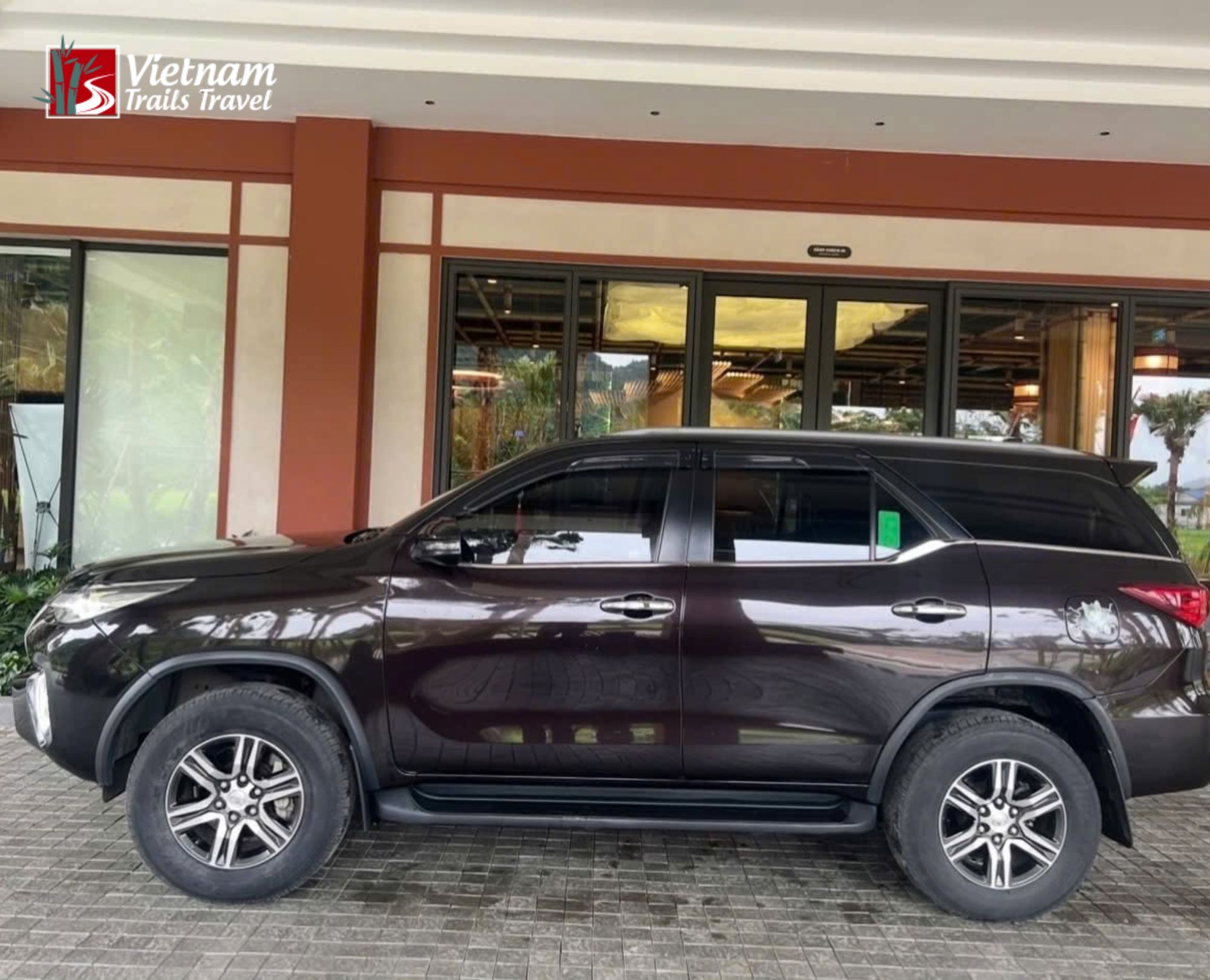 A private car from Hanoi waiting outside a modern building, ready for the journey to Hoang Su Phi