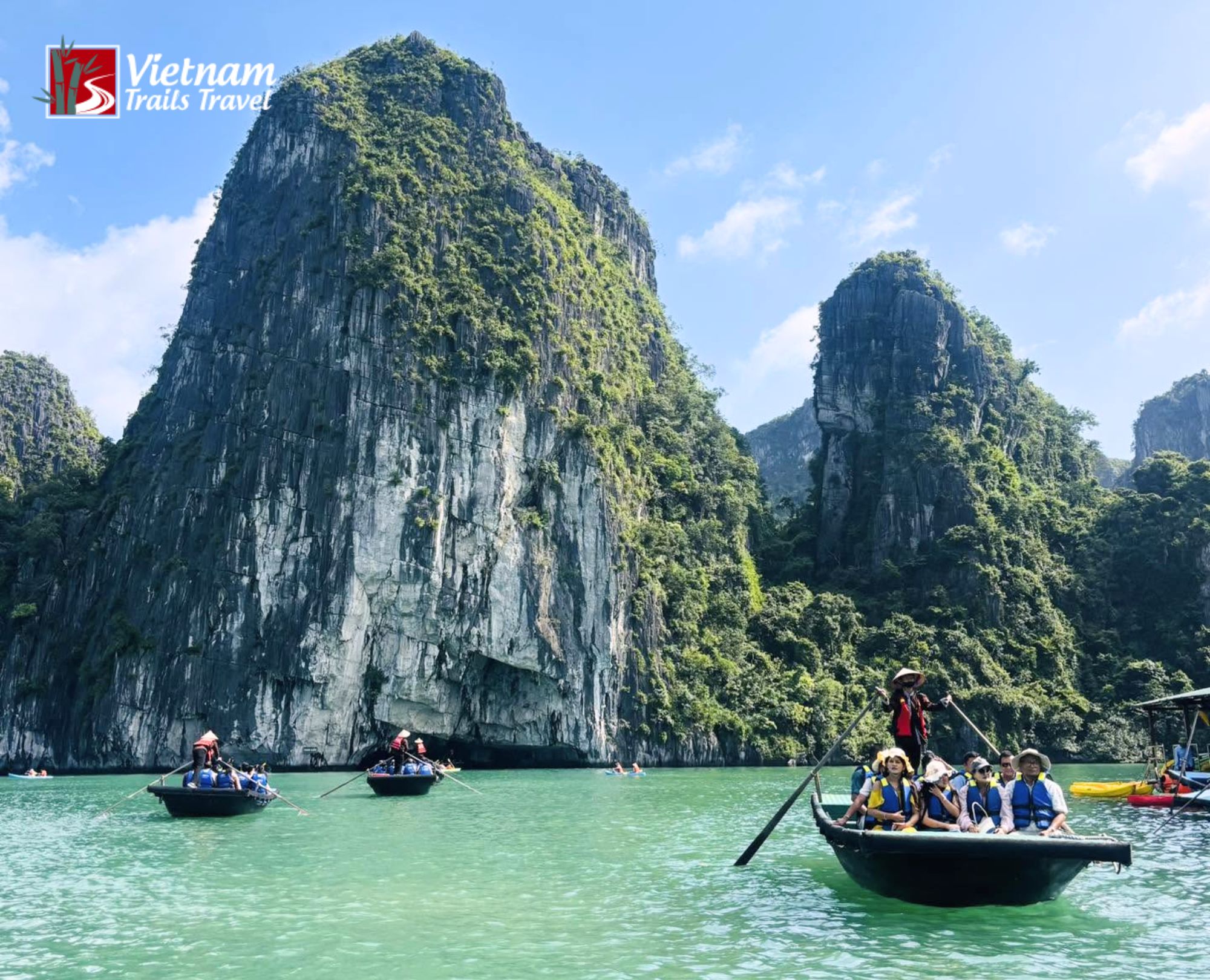 Bamboo boat tour past limestone karsts in the turquoise water of Halong Bay