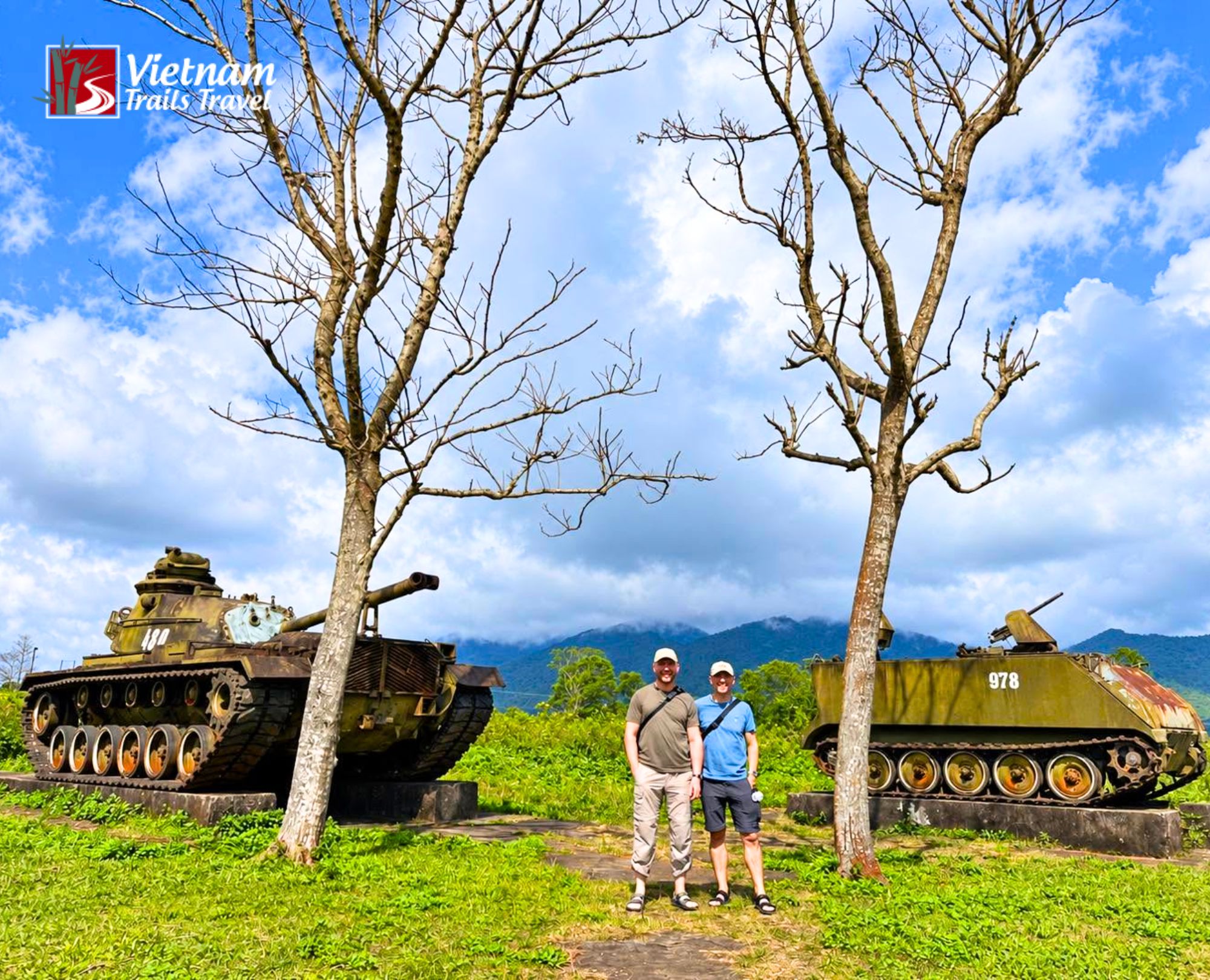 Foreign tourists who explore Khe Sanh Combat Base stand near authentic war machinery during a private Vietnam DMZ tour from Hue