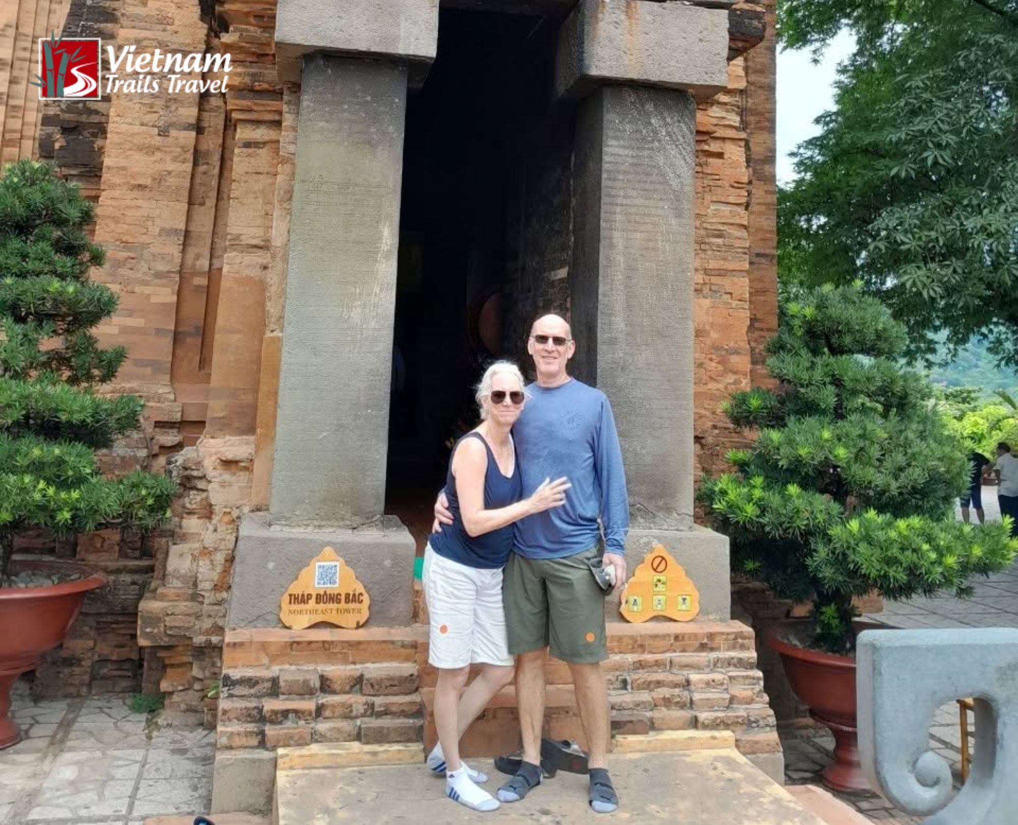Happy couple smiling in front of the ancient brick towers of Ponagar Tower