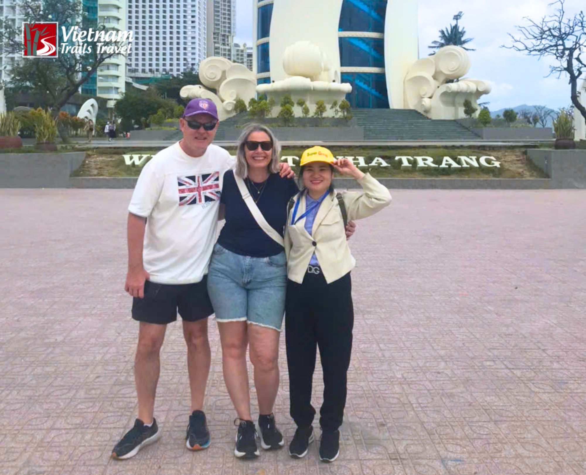 Local guide and two visitors smiling together under the Nha Trang city sign
