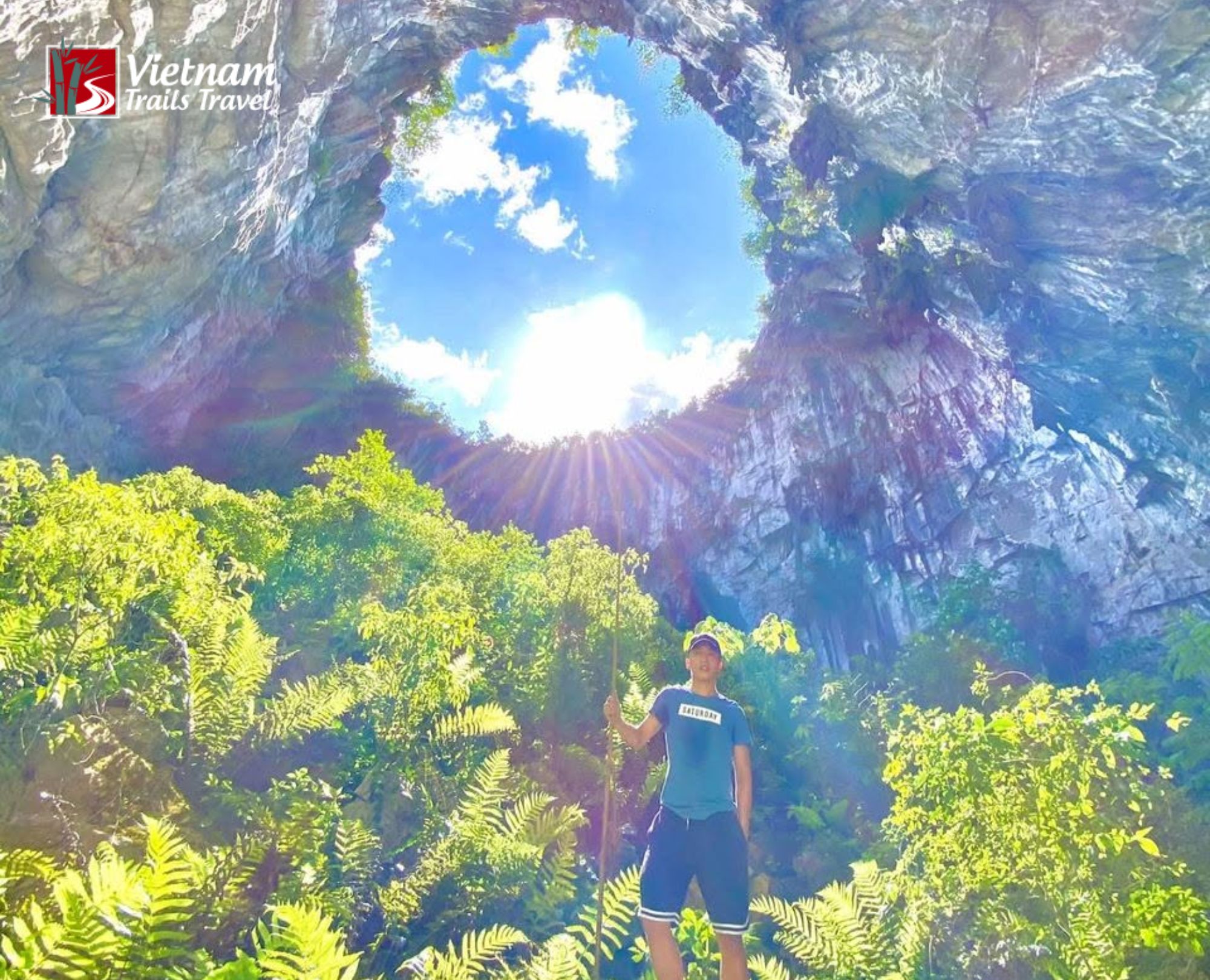 Man standing inside Meo Vac Sinkhole looking up at sunlight through the opening