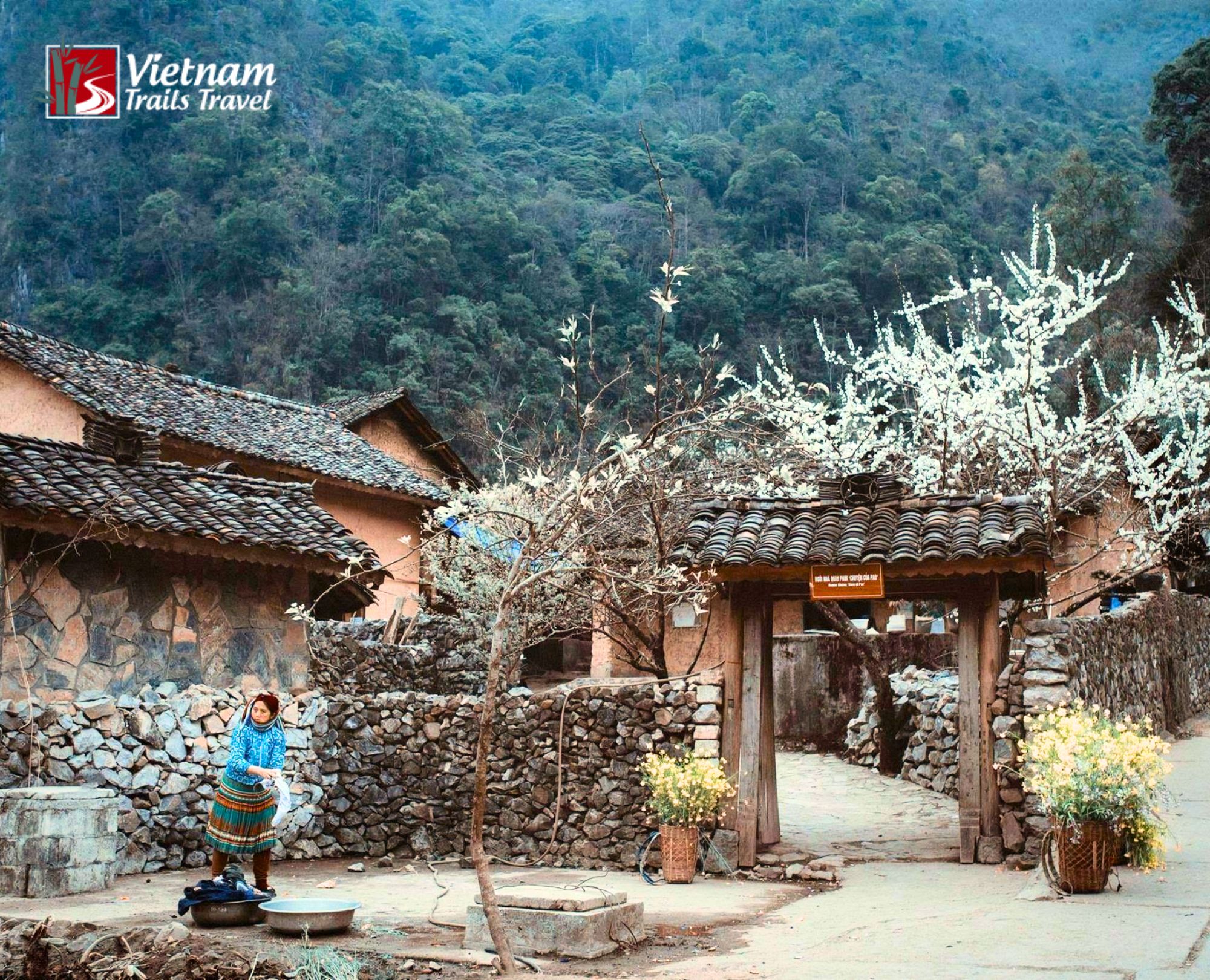 Pao's House and the film hamlet in Sung La Valley with a Hmong woman washing clothes by the rustic wooden gate