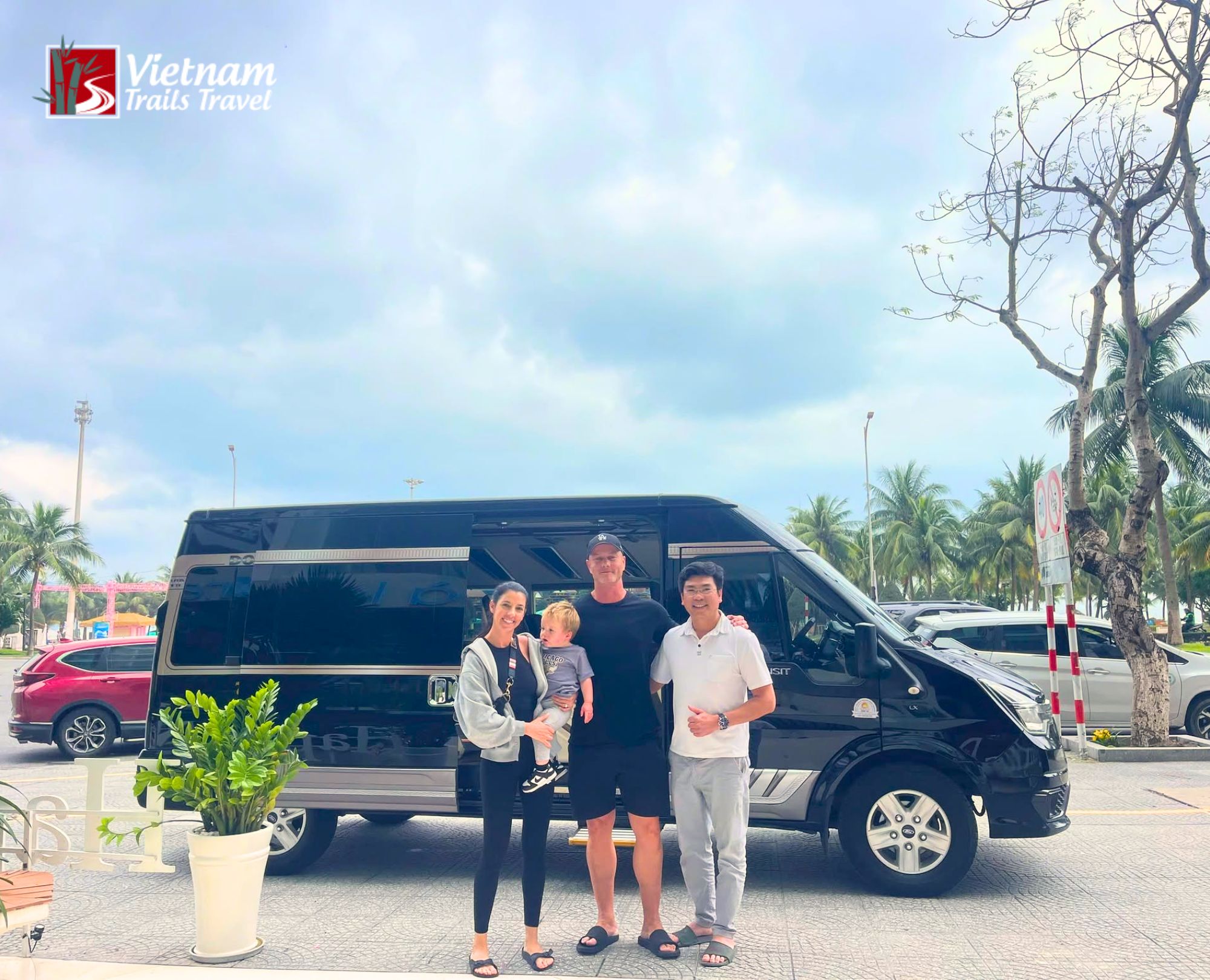 Professional driver welcoming family travelers next to a luxury limousine vehicle during a coastal transfer