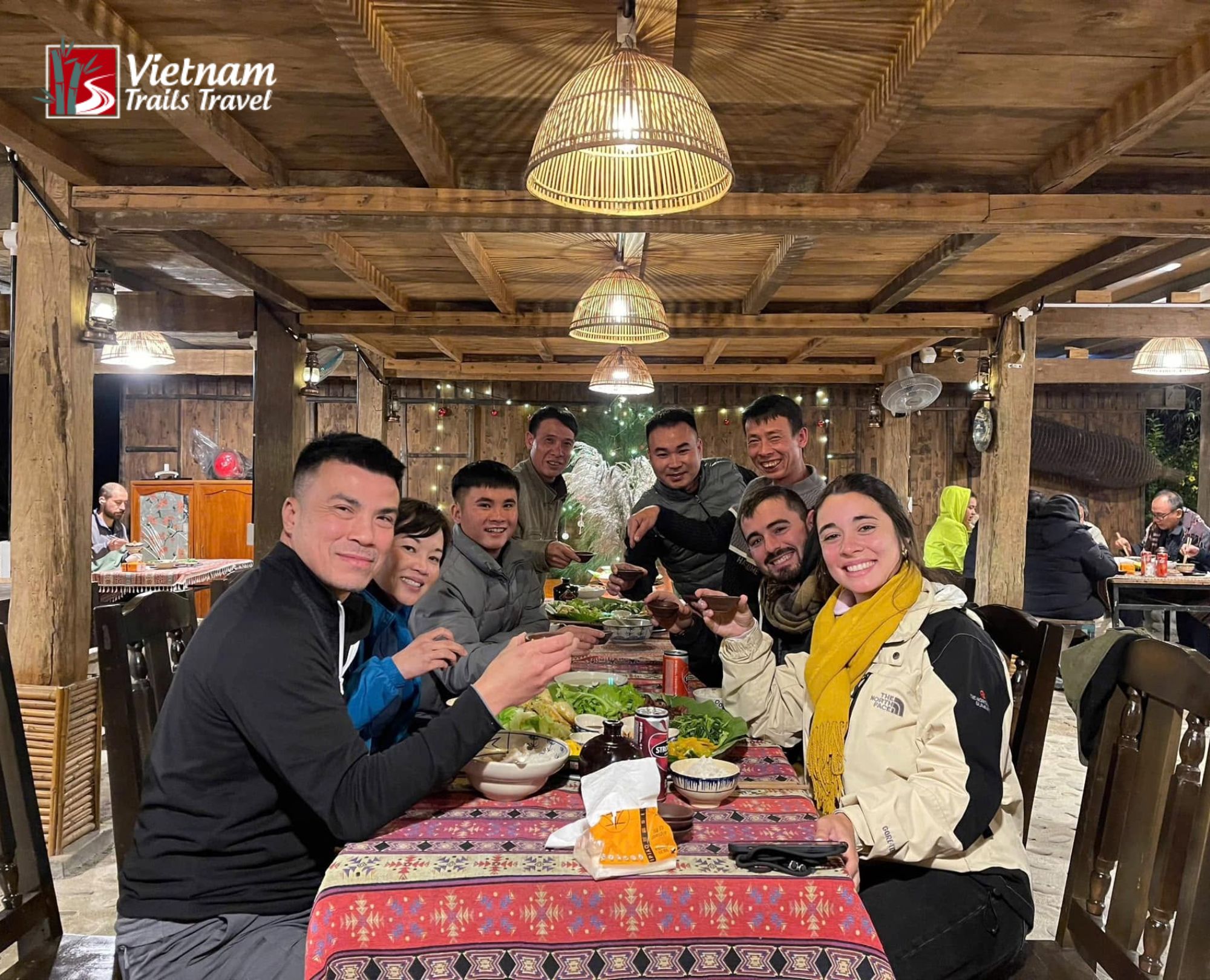 Smiling travelers having fun and eating local food at a cozy restaurant in Ha Giang city