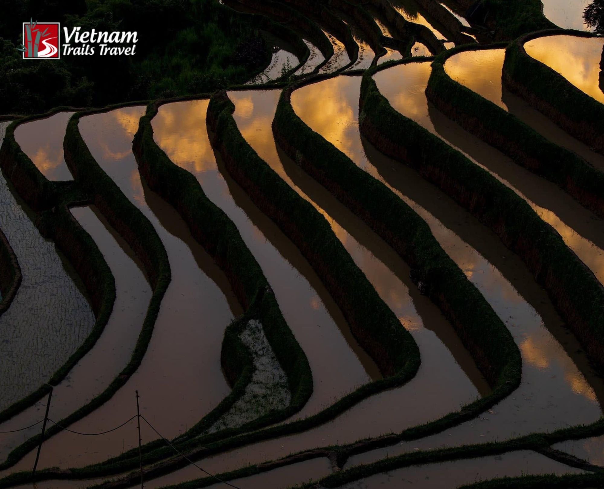 The flooded season in Hoang Su Phi, with submerged rice terraces reflecting a golden sky