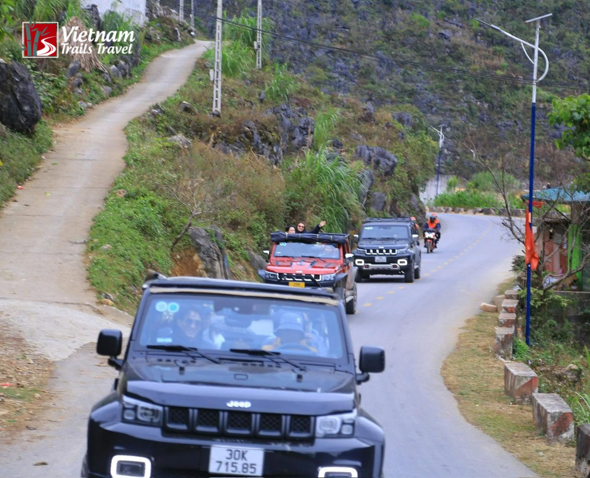 Tourists enjoying a road trip in SUV cars while traveling from Ha Giang city to Suoi Thau through mountain passes